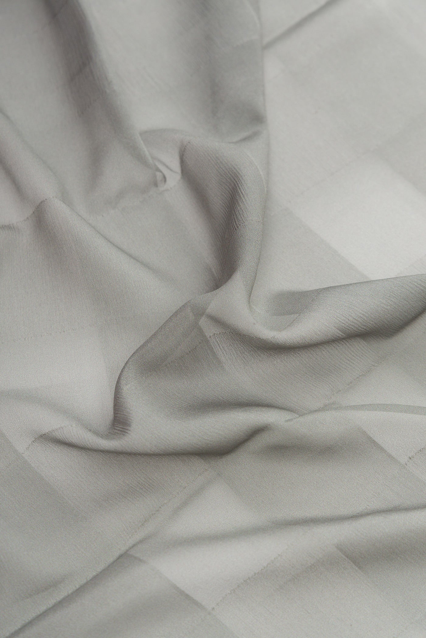 Close up of Grey Dual Tone Mysore Crepe Saree with Printed design on the body and Fancy Border.  displaying folds