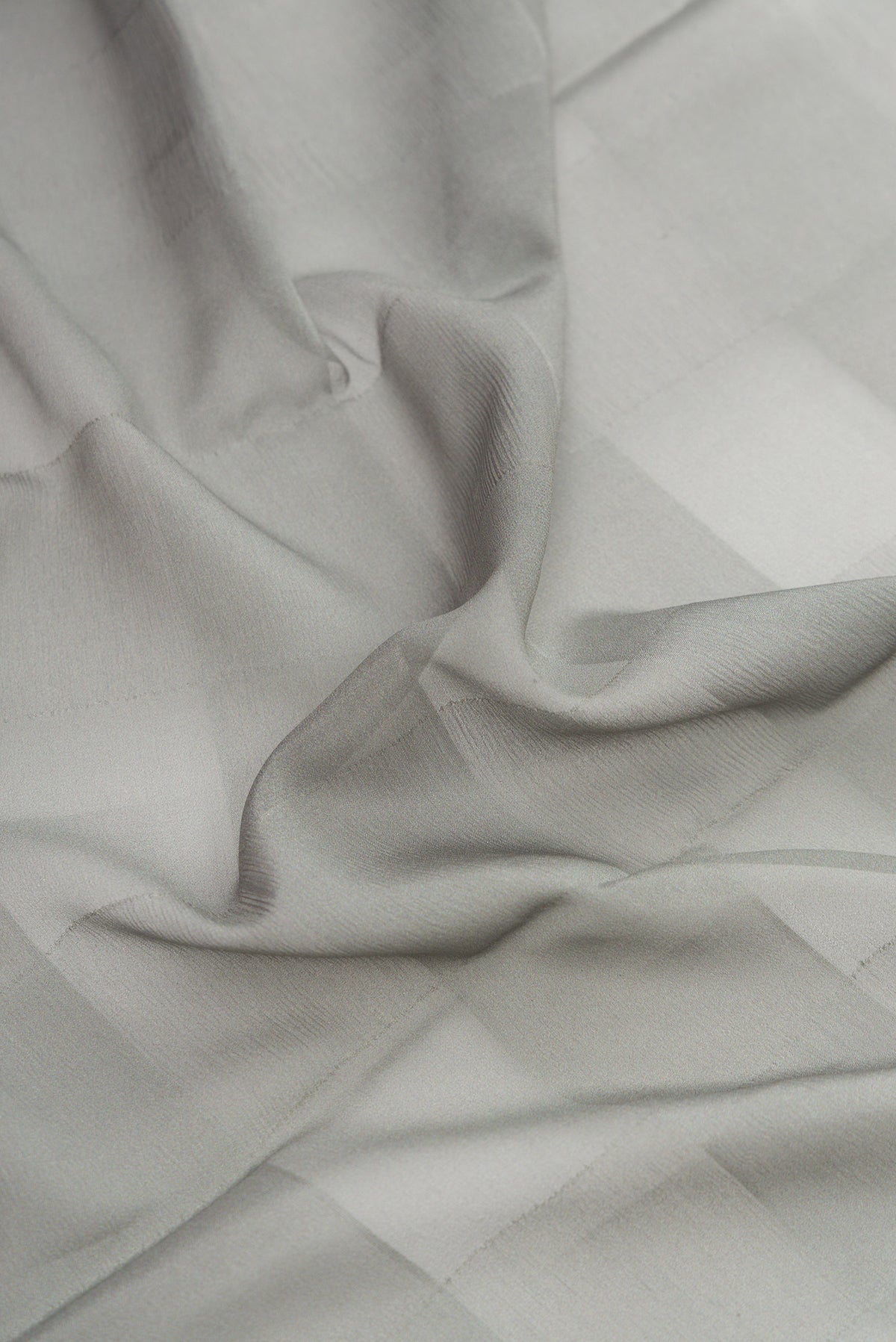 Close up of Grey Dual Tone Mysore Crepe Saree with Printed design on the body and Fancy Border.  displaying folds