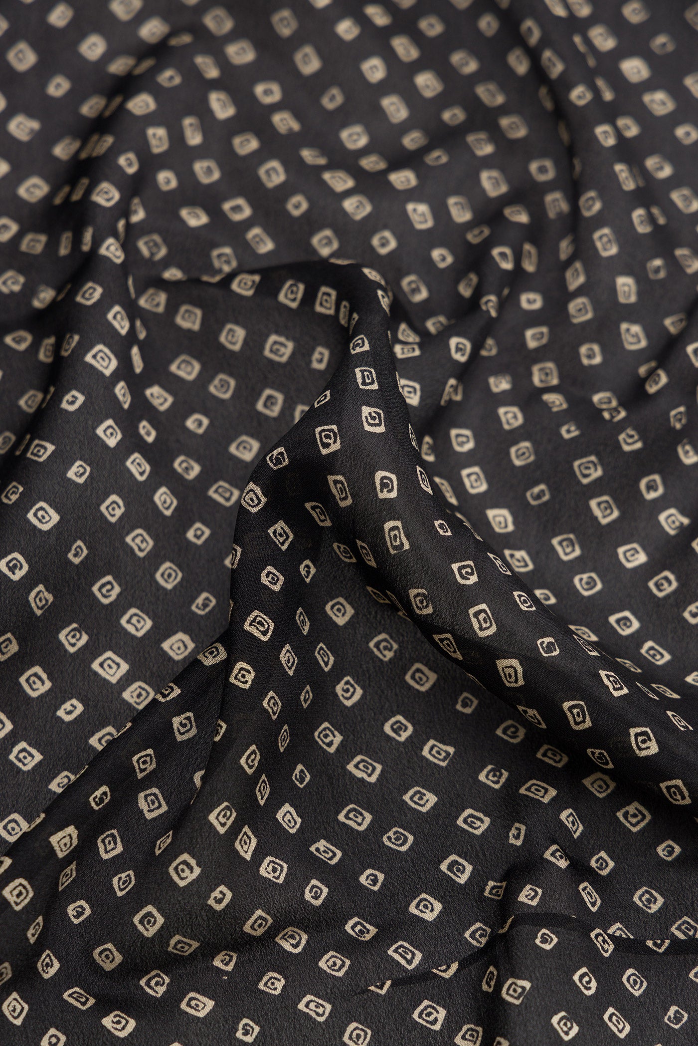 Close up of Black Dual Tone Mysore Crepe Saree with Bandhani Print on the body and Zari Border.  displaying folds