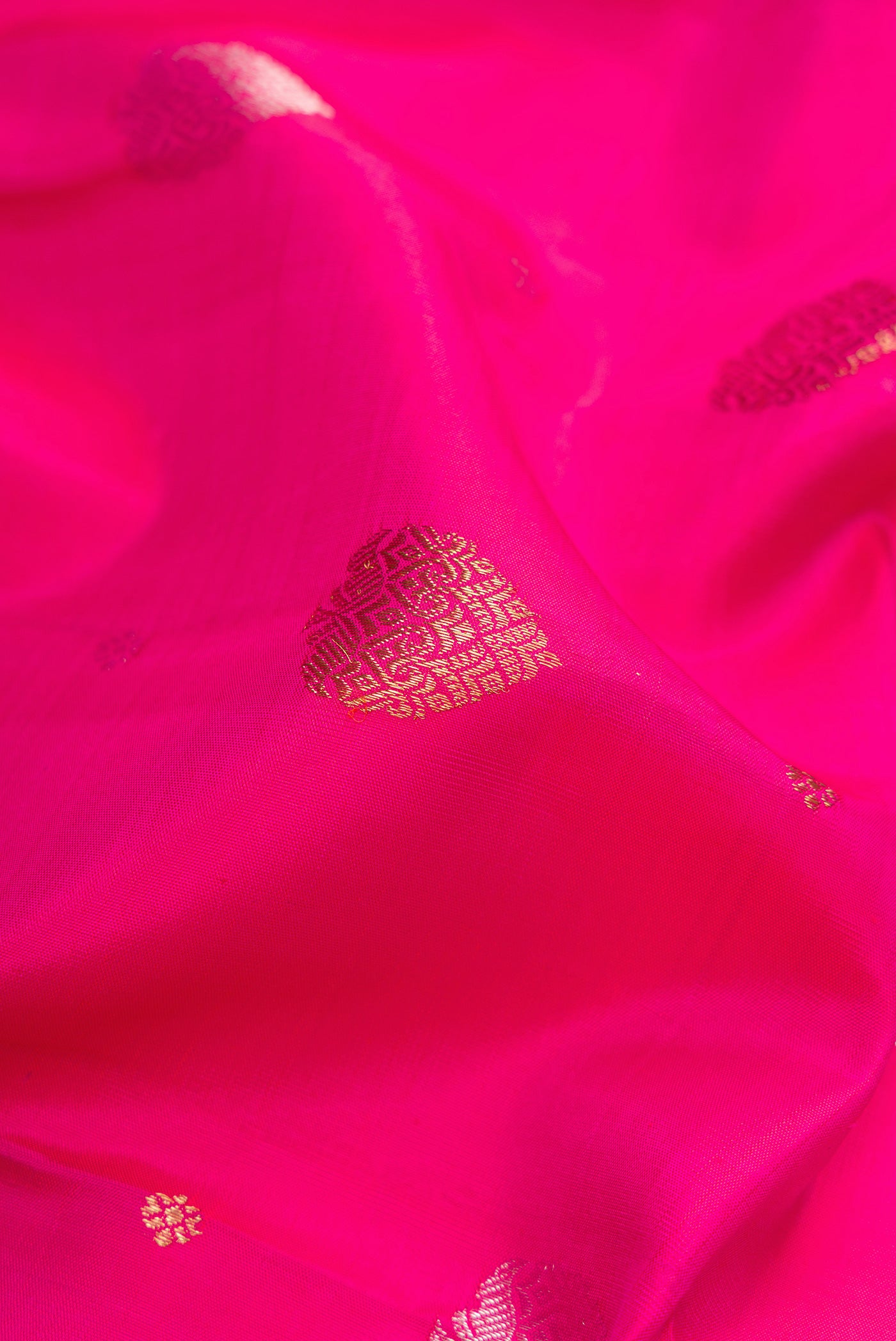 Close up of Pure Silk Pure Zari Rani Pink Kanchipuram Saree with Zari Butta on the body and Zari Border.  displaying folds