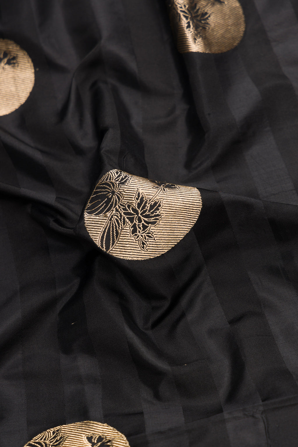 Close up of Black Dual Tone Banarasi Silk Saree with Zari Butta on the body and Without Border.  displaying folds