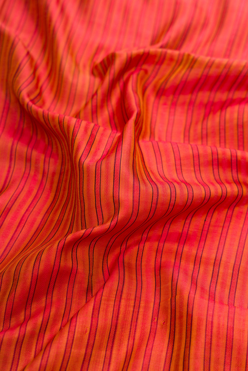 Close up of Red Dual Tone Rajkot Patola Silk Saree with Stripes on the body and Paithani Border.  displaying folds
