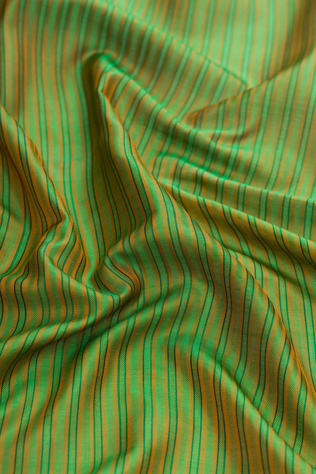 Close up of Green Dual Tone Rajkot Patola Silk Saree with Stripes on the body and Paithani Border.  displaying folds