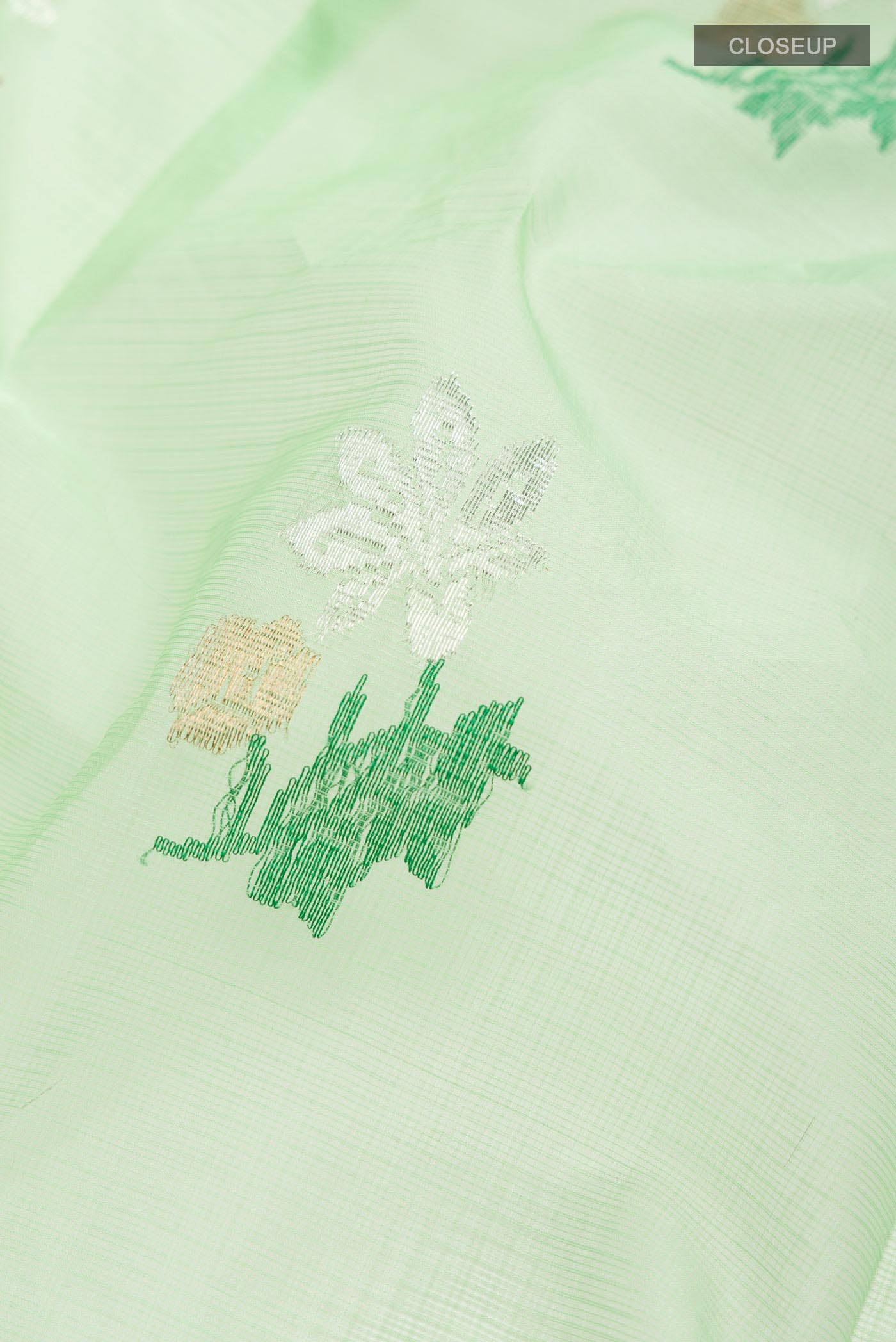 Close up of Green Kota Silk Saree with Zari And Thread Butta on the body and Zari Border displaying folds