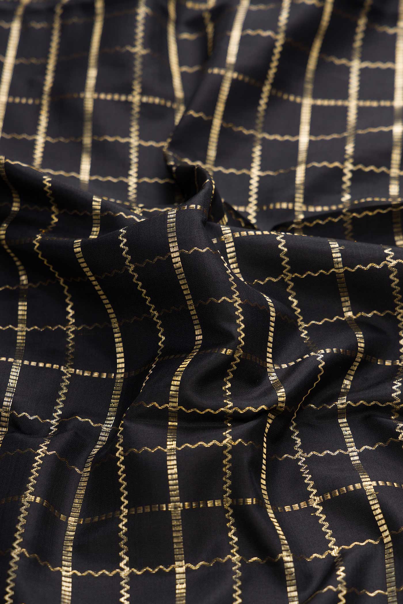 Close up of Black Dual Tone Kanchipuram Silk Saree with Checked design on the body and Zari Border displaying folds