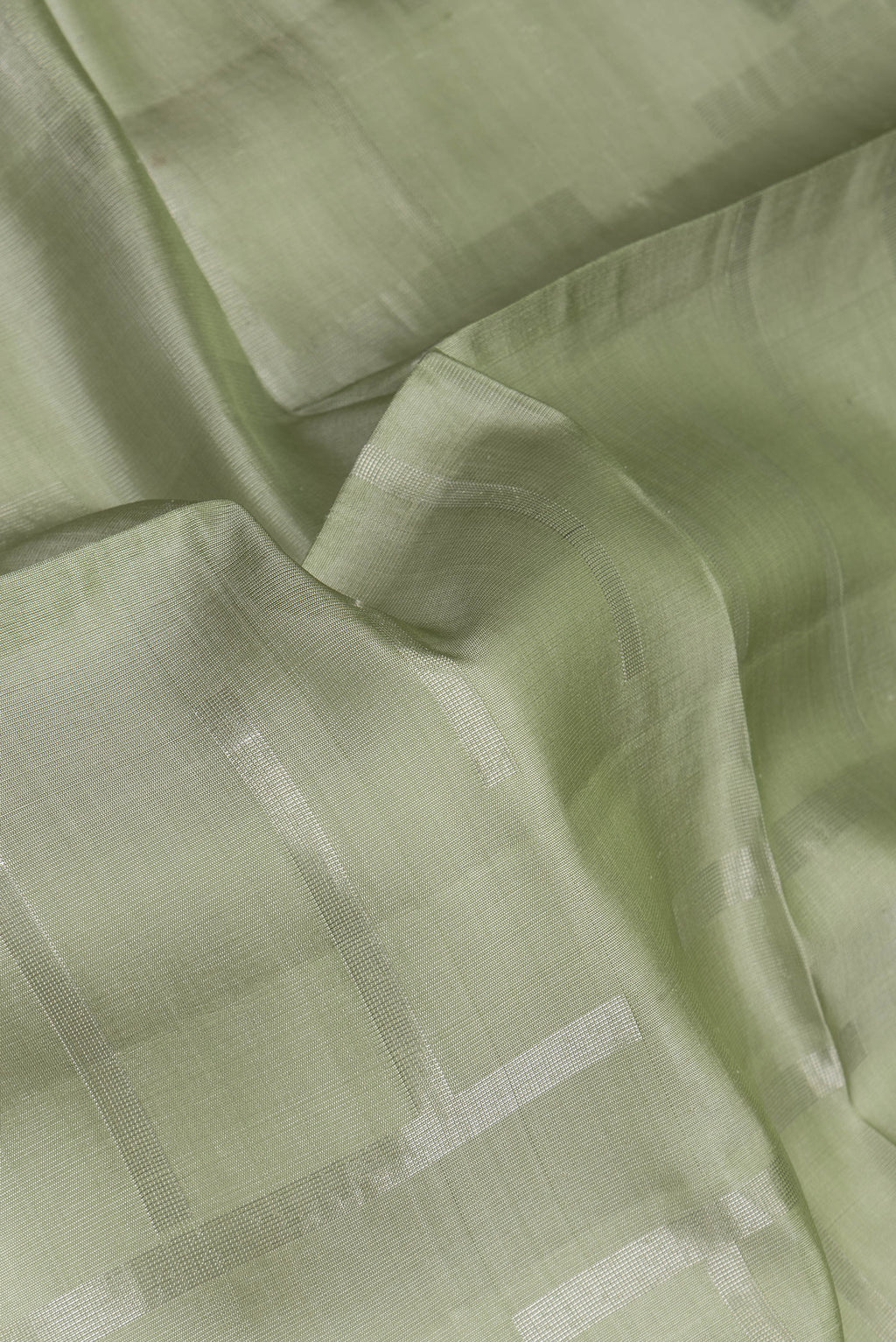 Close up of Pista Green Tussar Silk Saree with Checked design on the body and Zari Border.  displaying folds