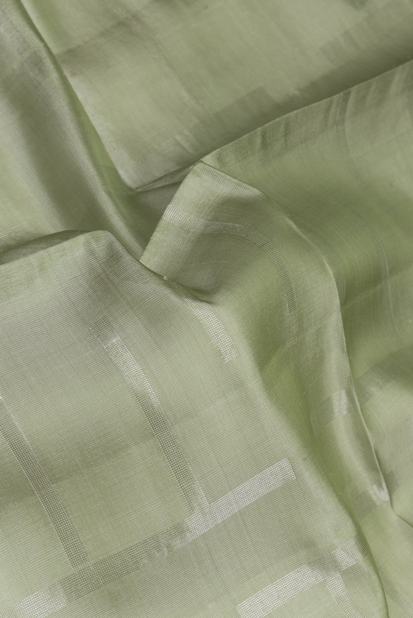 Close up of Pista Green Tussar Silk Saree with Checked design on the body and Zari Border.  displaying folds