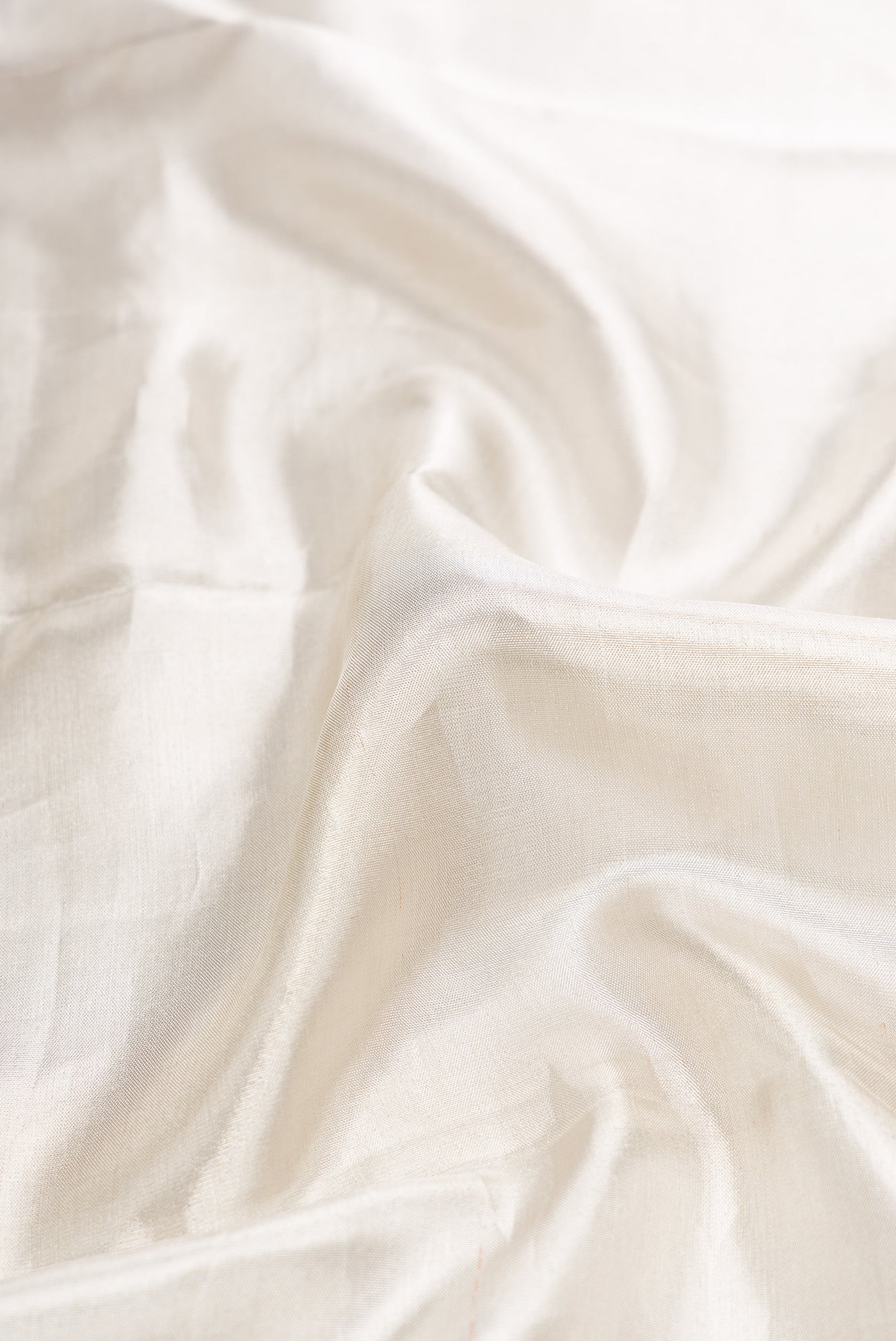 Close up of Off White Dual Tone Kanchipuram Tissue Silk Saree with Plain Body and Zari Border.  displaying folds