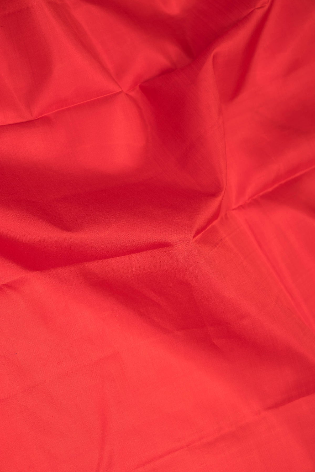 Close up of Red Dual Tone Kanchipuram Saree with Plain Body and Zari Border displaying folds