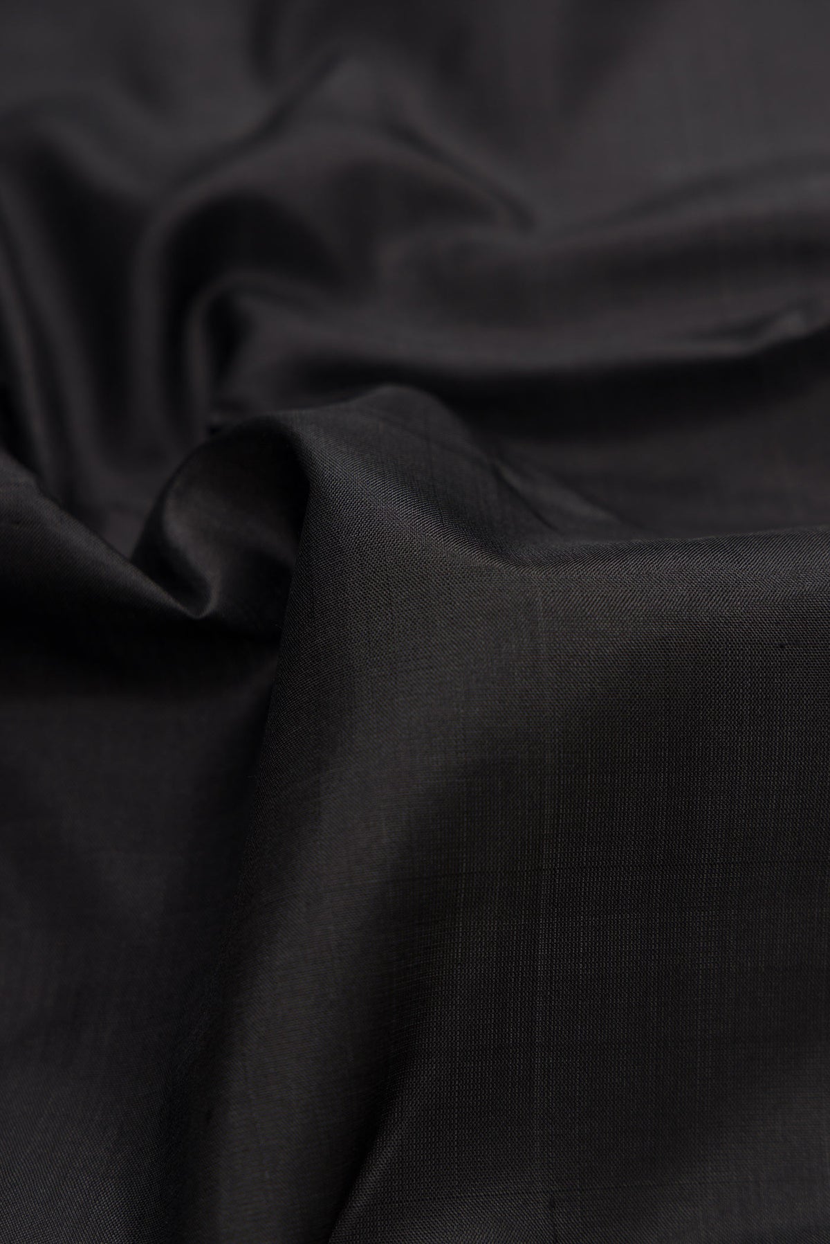 Close up of Black Dual Tone Kanjivaram Silk Saree with Plain Body and Zari Border.  displaying folds