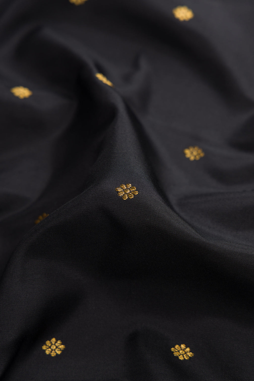 Close up of Pure Silk Pure Zari Black Dual Tone Kanchipuram Saree with Zari Butta on the body and Zari Border displaying folds