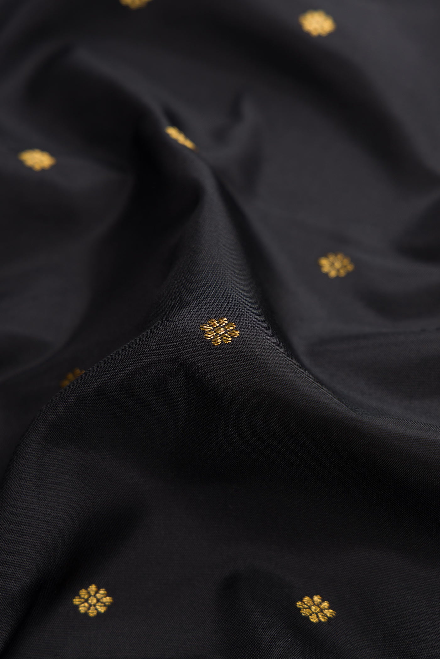 Close up of Pure Silk Pure Zari Black Dual Tone Kanchipuram Saree with Zari Butta on the body and Zari Border displaying folds