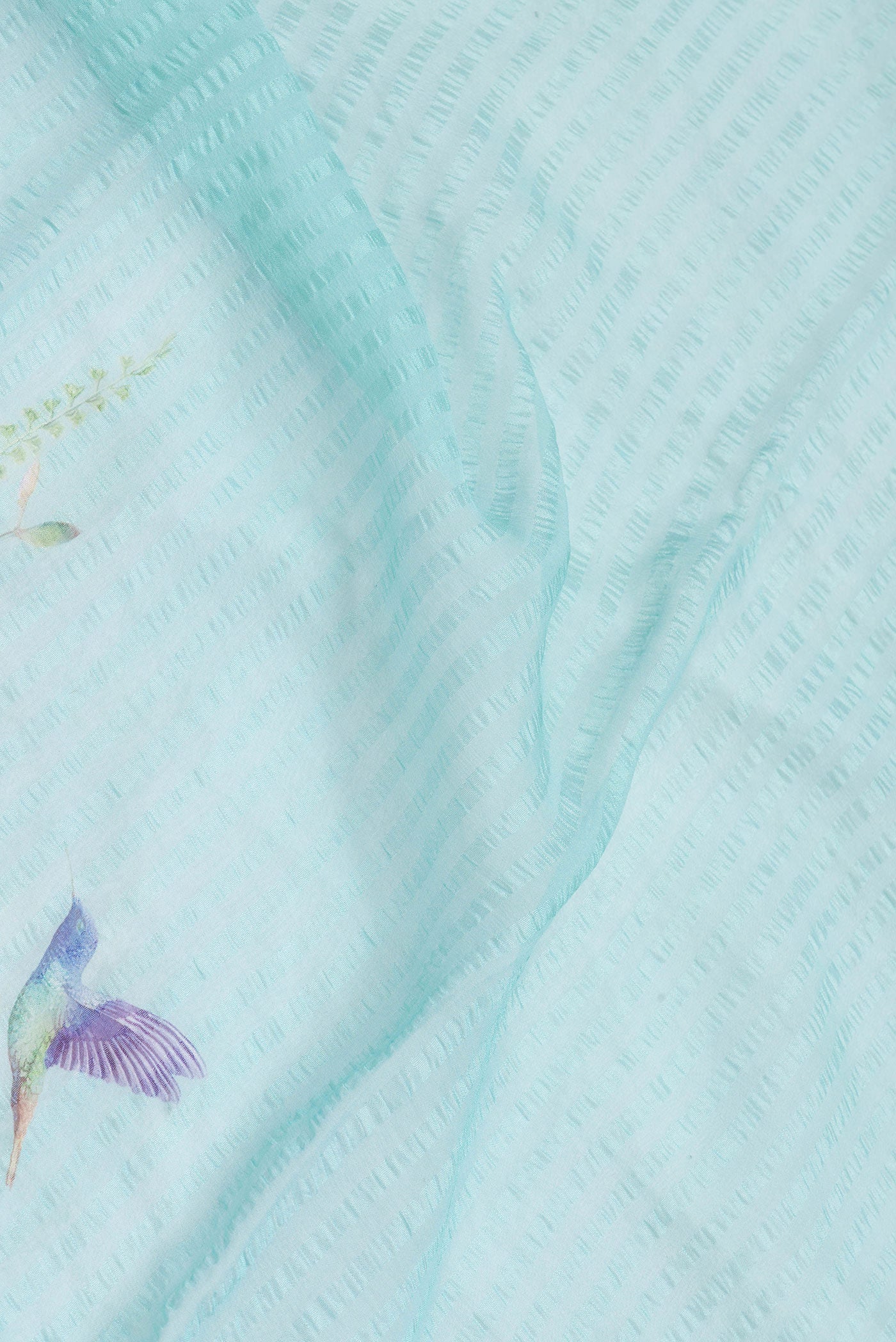 Close up of Sky Blue Dual Tone Mysore Chiffon Saree with Printed design on the body and Thread Border.  displaying folds