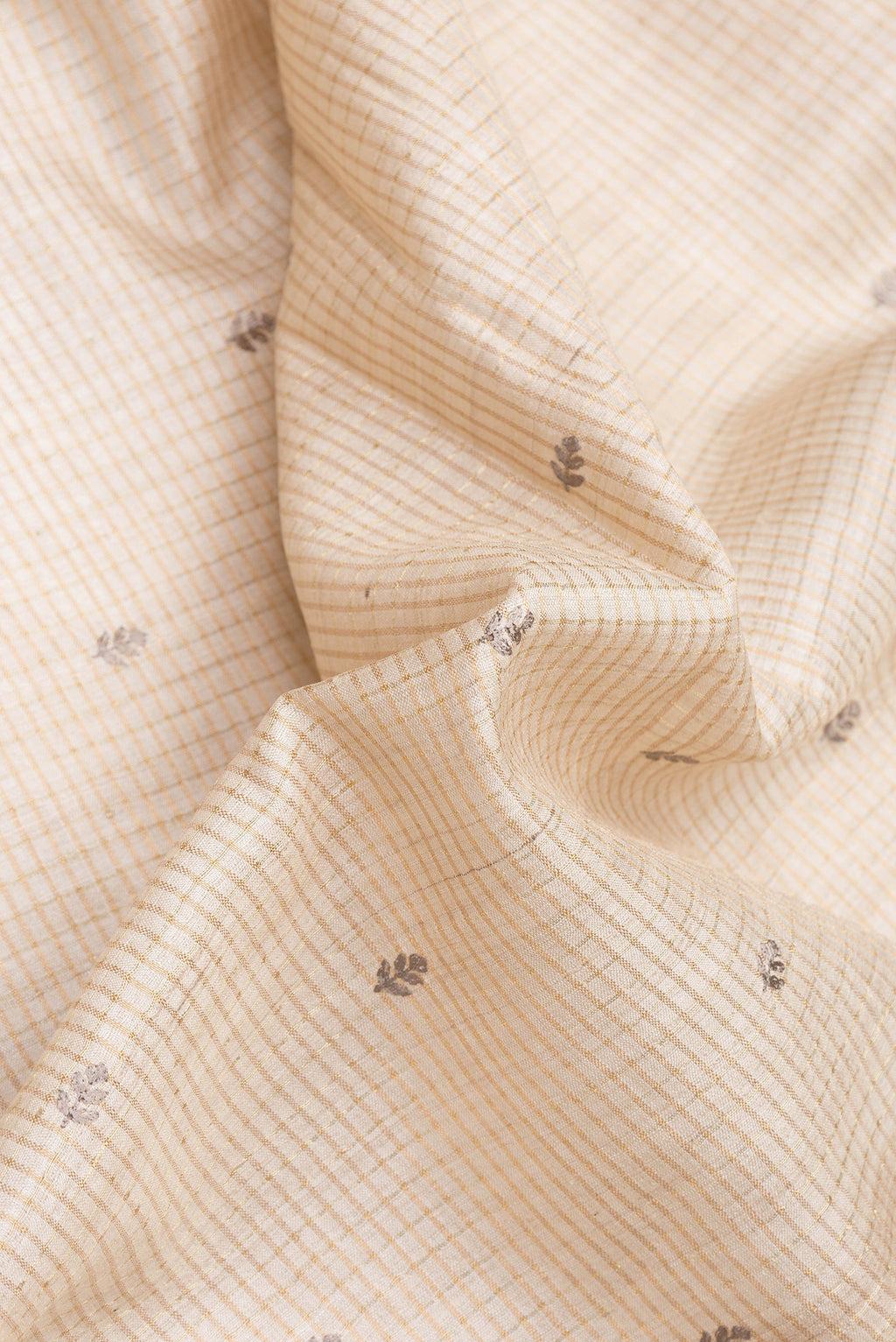Close up of Beige Dual Tone Tussar Silk Saree with Checked design on the body and Embroidery Border.  displaying folds