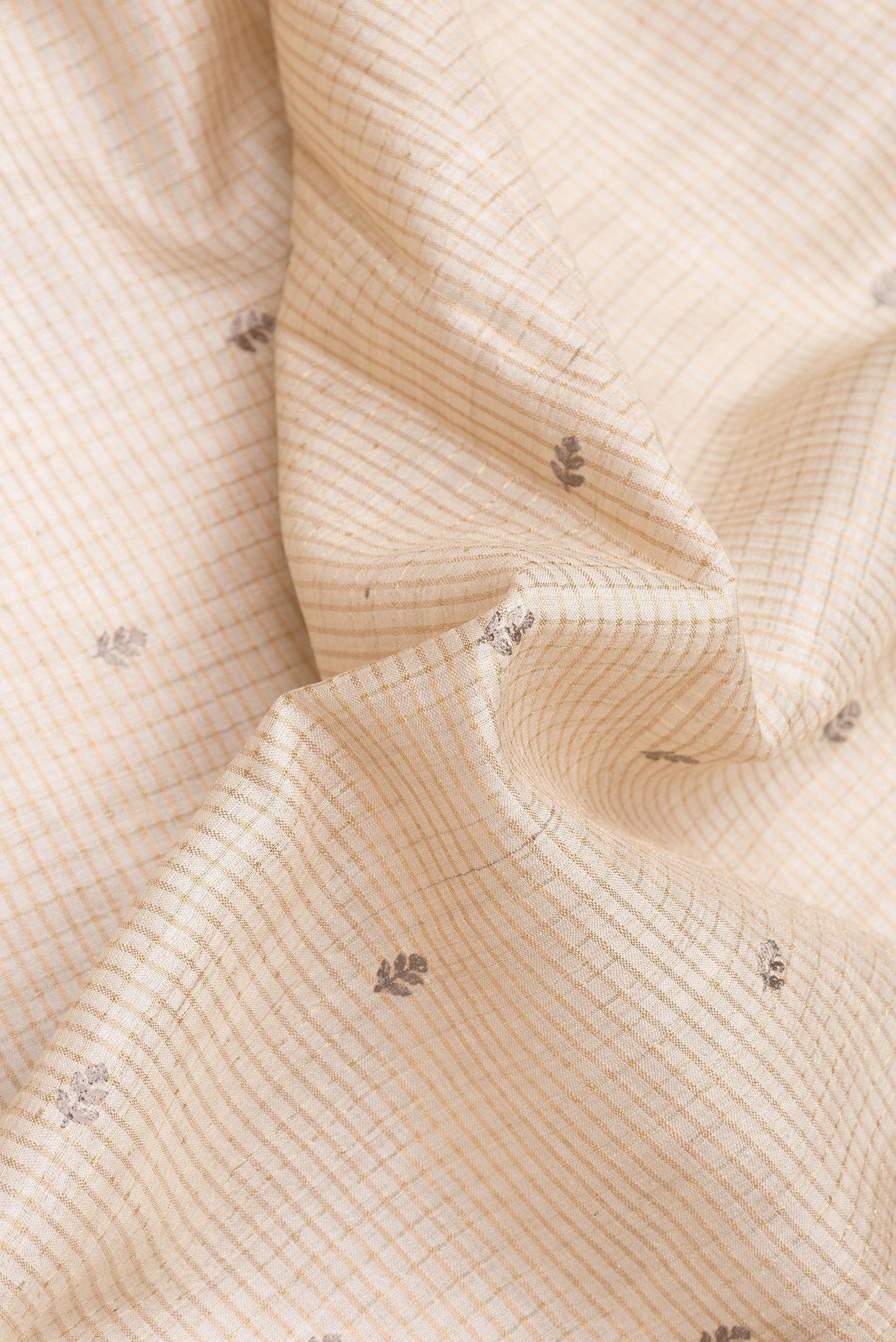 Close up of Beige Dual Tone Tussar Silk Saree with Checked design on the body and Embroidery Border.  displaying folds
