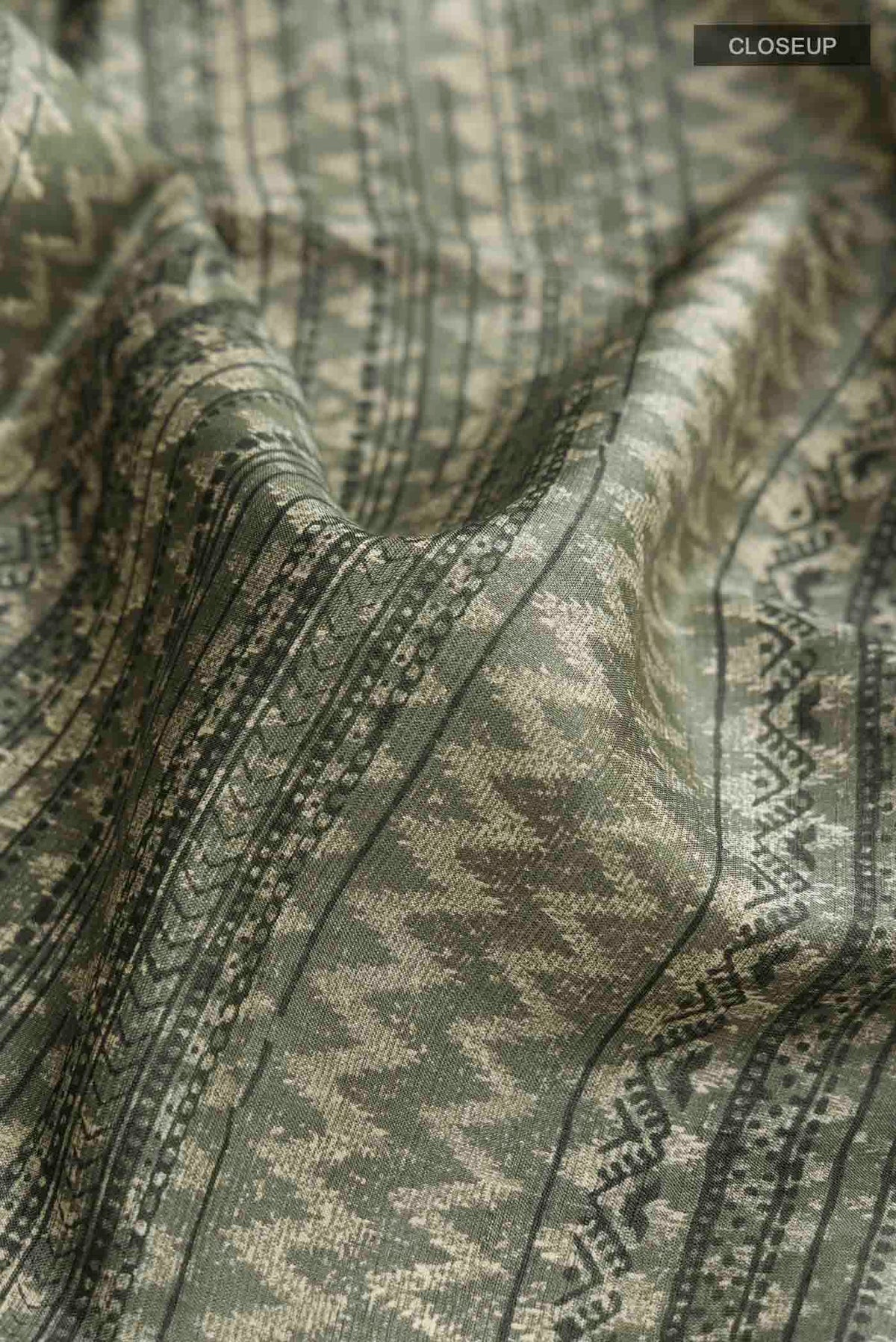 Close up of Green Tussar Silk Saree with Printed design on the body and Plain Border displaying folds