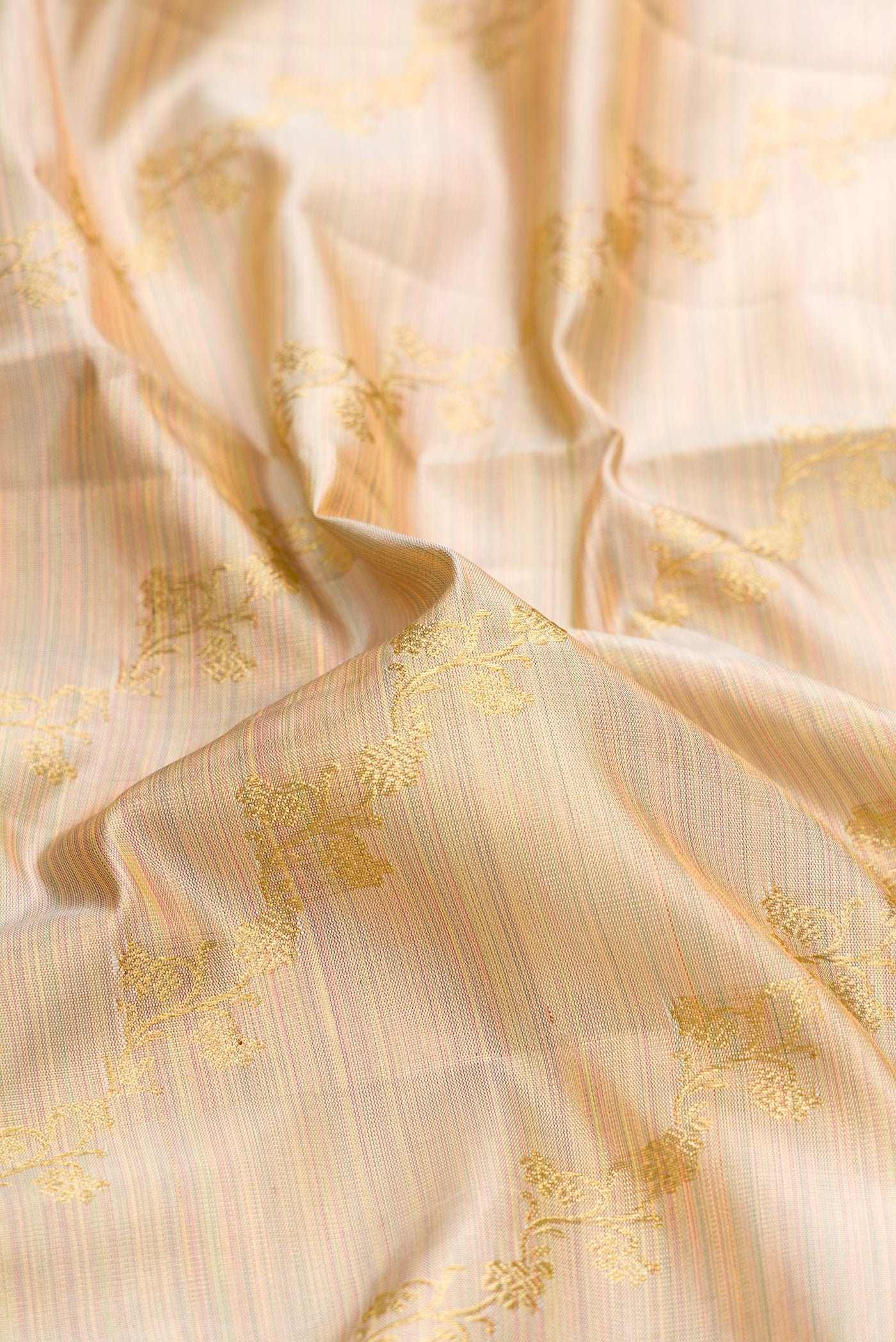 Close up of Rose Gold Dual Tone Kanchipuram Tissue Silk Saree with Zari Brocade on the body and Zari Border.  displaying folds