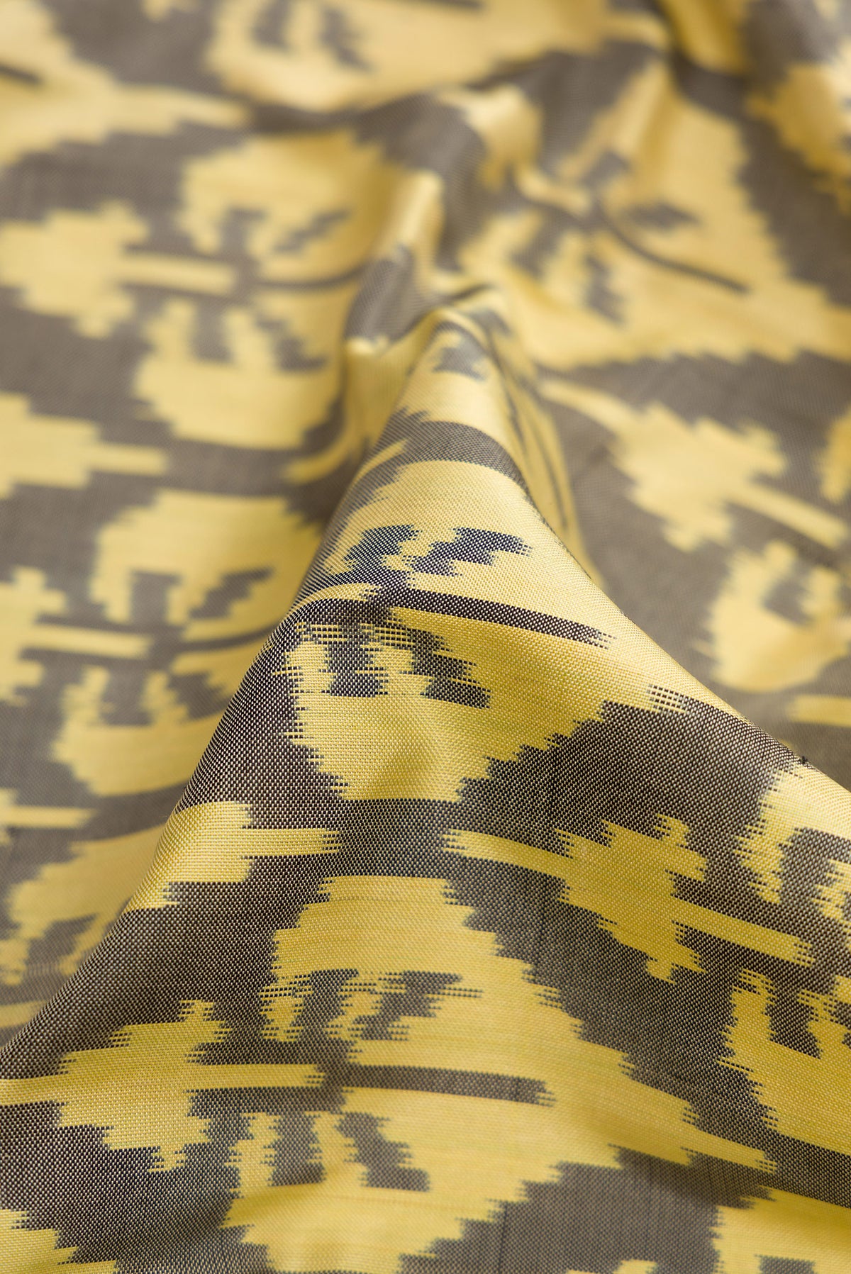 Close up of Sandal Dual Tone Double Ikat Saree with Ikat Print on the body and Thread Border.  displaying folds