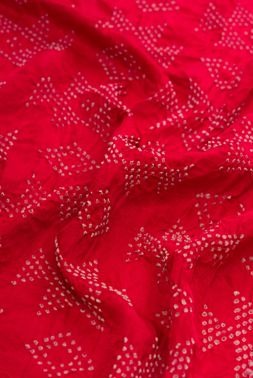 Close up of Red Dual Tone Bandhani Silk Saree with Bandhani Print on the body and Without Border.  displaying folds