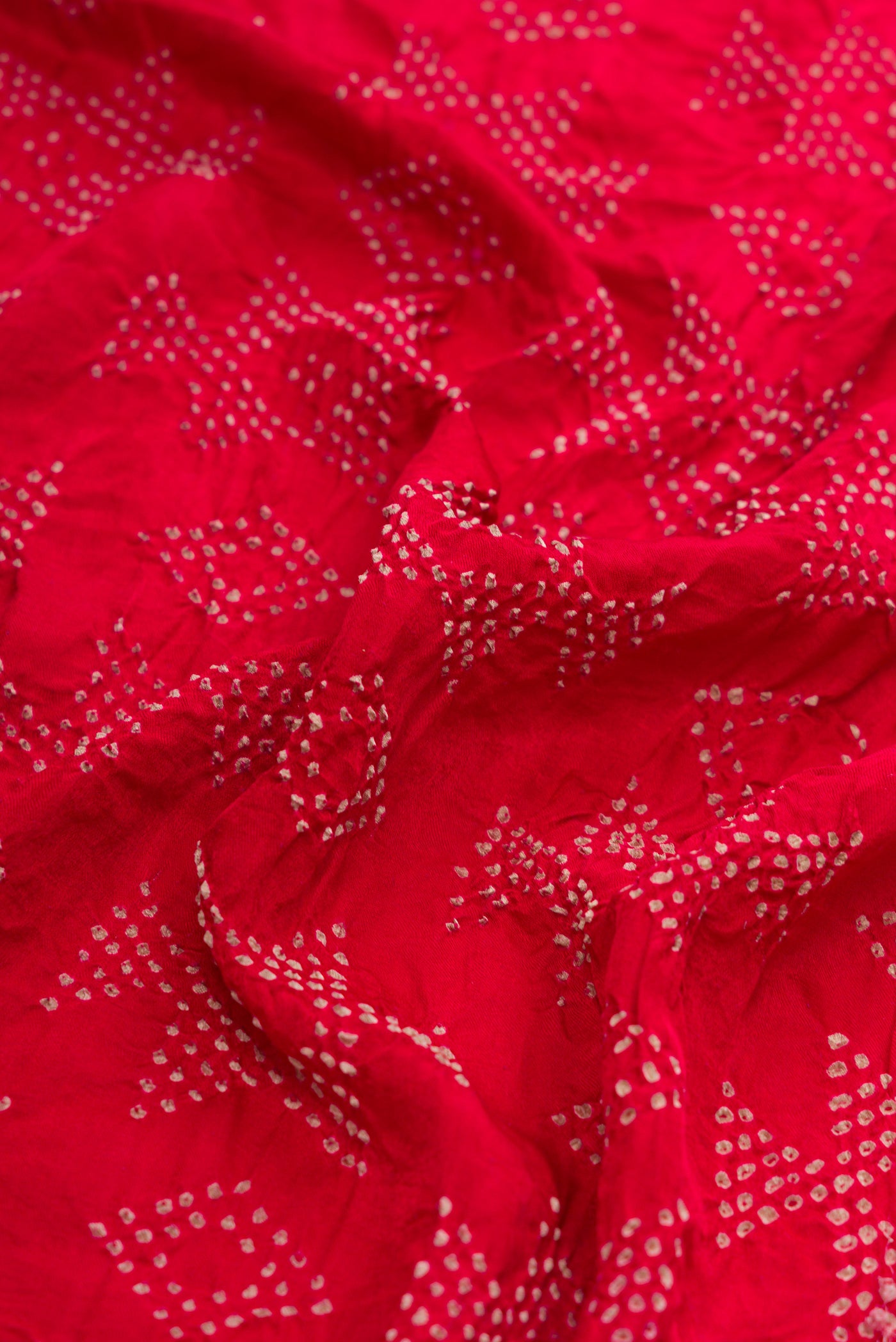 Close up of Red Dual Tone Bandhani Silk Saree with Bandhani Print on the body and Without Border.  displaying folds