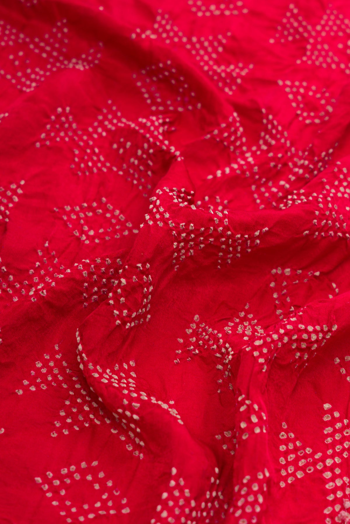 Close up of Red Dual Tone Bandhani Silk Saree with Bandhani Print on the body and Without Border.  displaying folds