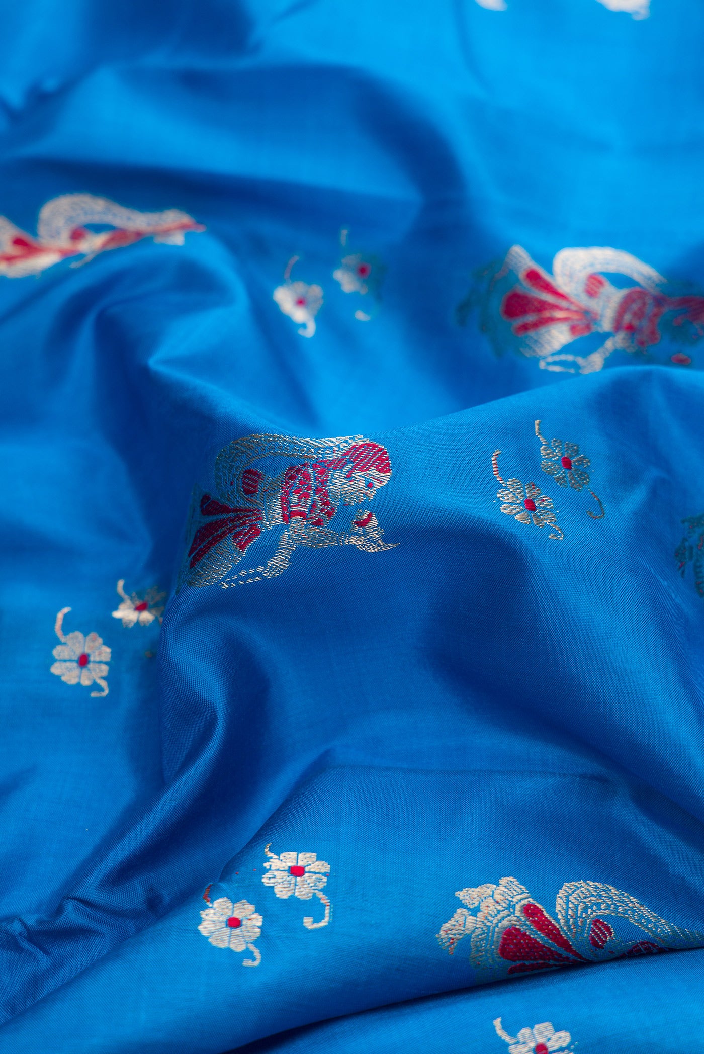 Close up of Sky Blue Dual Tone Baluchari Silk Saree with Zari And Thread Butta on the body and Fancy Border.  displaying folds