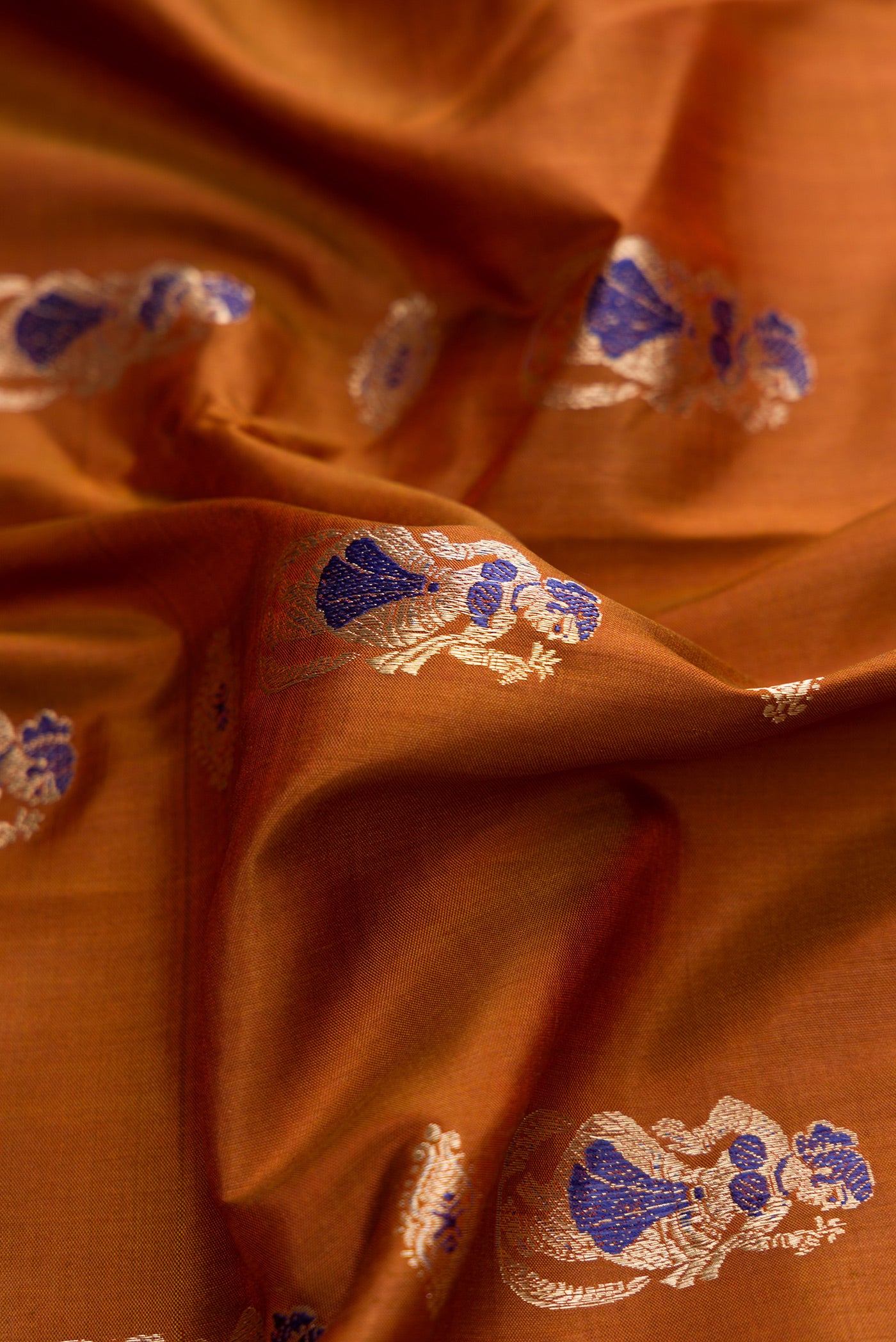 Close up of Caramel Dual Tone Baluchari Silk Saree with Zari And Thread Butta on the body and Fancy Border.  displaying folds