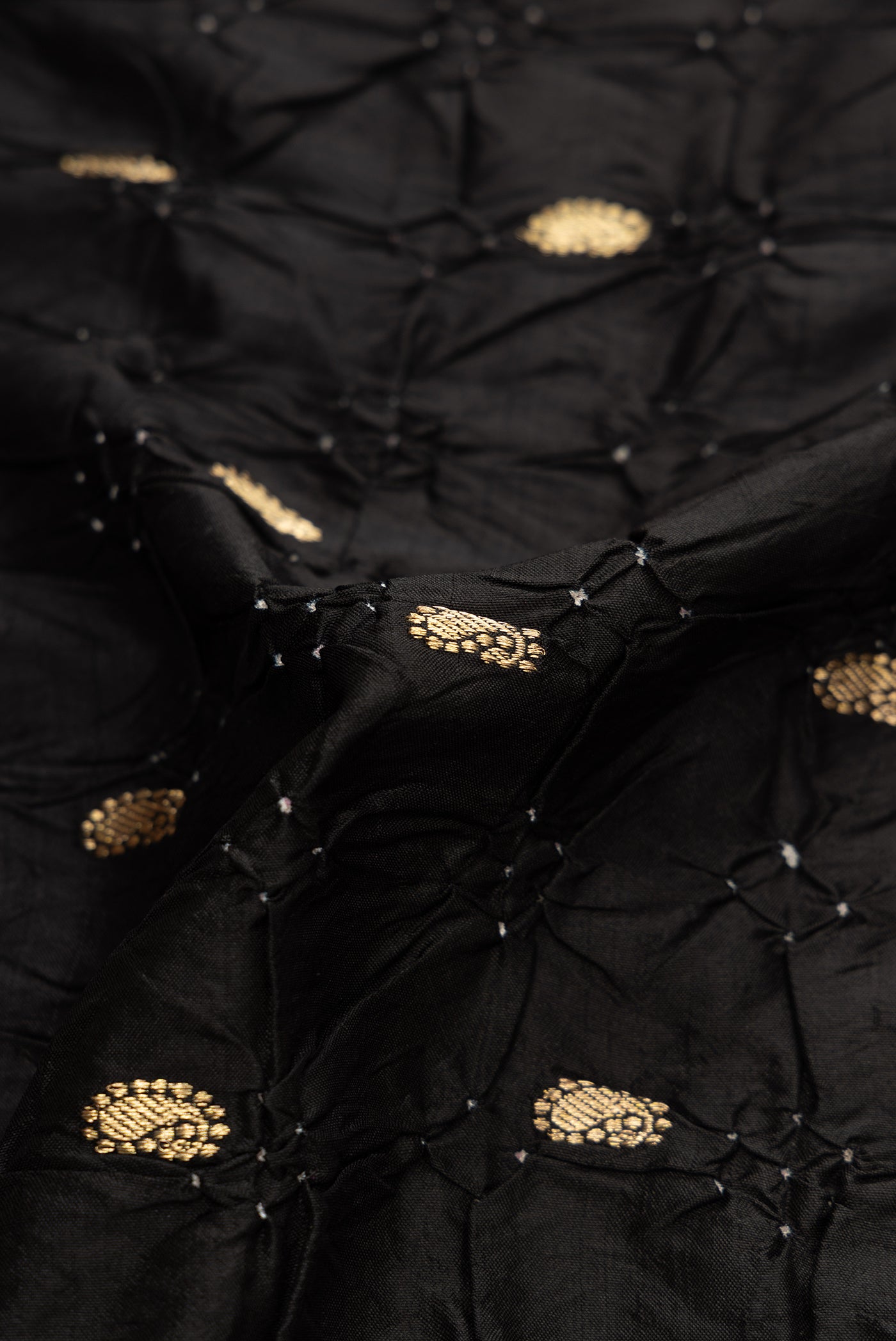 Close up of Black Dual Tone Bandhani Silk Saree with Bandhani Print on the body and Zari Border.  displaying folds