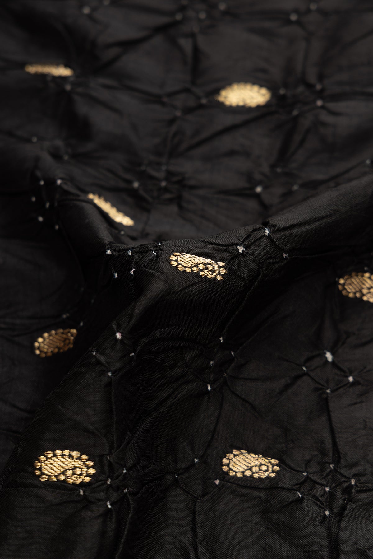 Close up of Black Dual Tone Bandhani Silk Saree with Bandhani Print on the body and Zari Border.  displaying folds