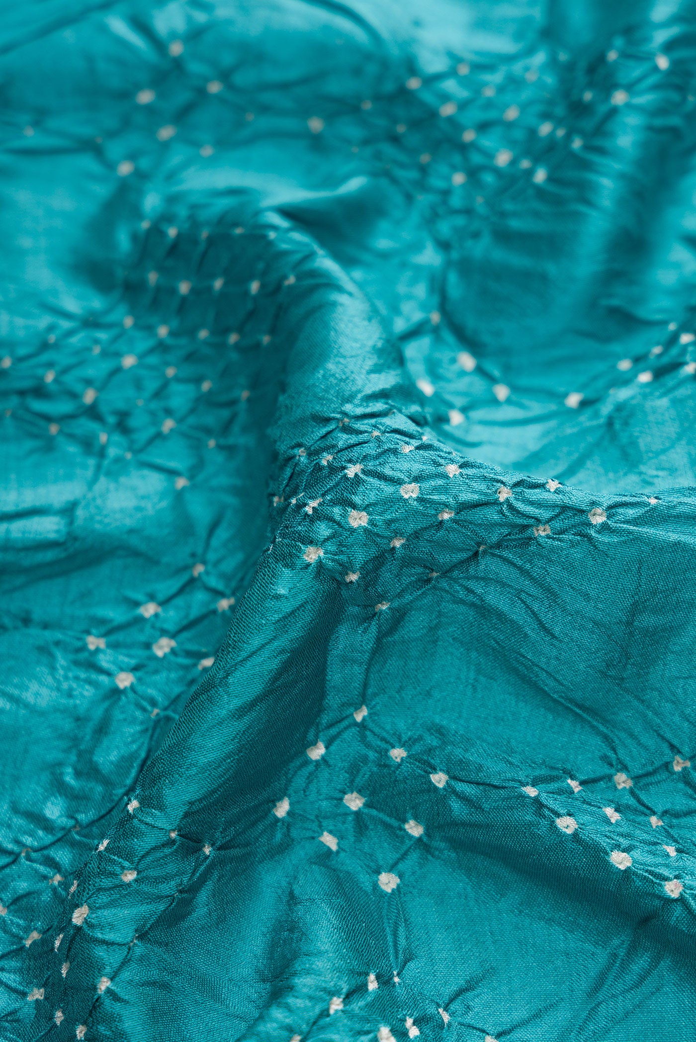 Close up of Peacock Blue Dual Tone Bandhani Silk Saree with Bandhani Print on the body and Zari Border.  displaying folds