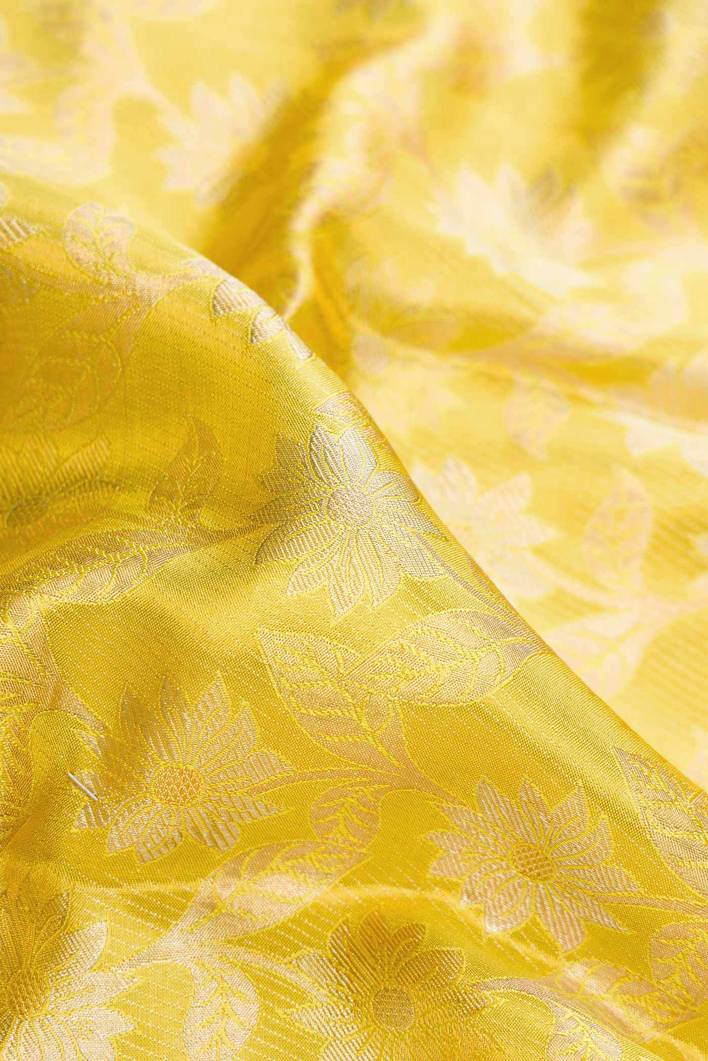 Close up of Lemon Yellow Dual Tone Kanchipuram Tissue Silk Saree with Zari Brocade on the body and Zari Border.  displaying folds