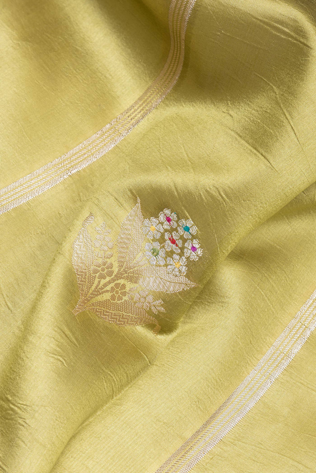 Close up of Green Tussar Silk Saree with Zari Butta on the body and Zari Border.  displaying folds