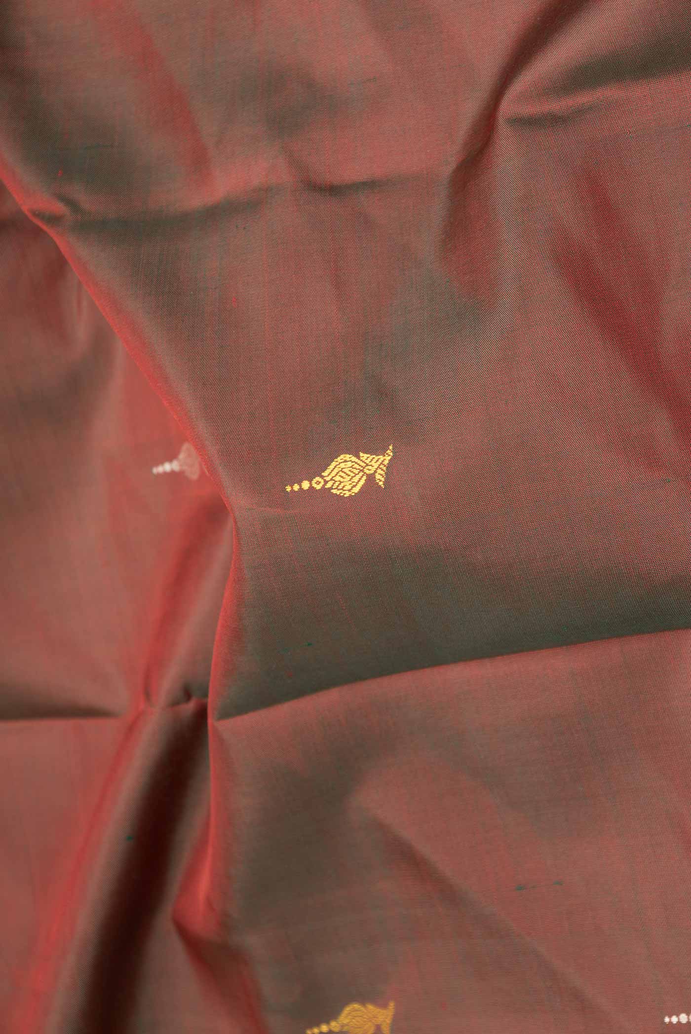 Close up of Maroon Dual Tone Kanchipuram Saree with Zari Butta on the body and Thread Border displaying folds