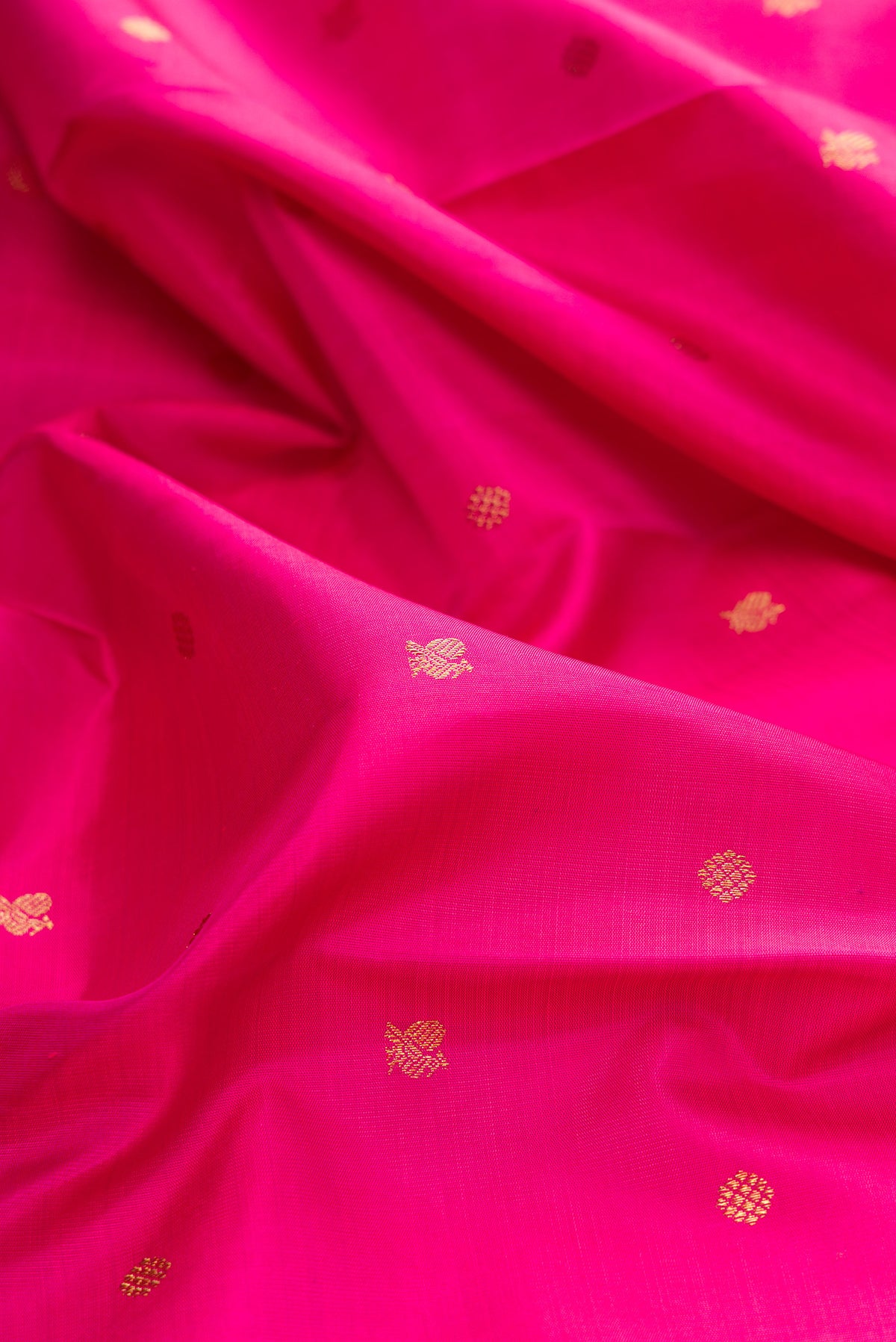 Close up of Pure Silk Pure Zari Pink Kanjivaram Saree with Zari Butta on the body and Zari Border.  displaying folds