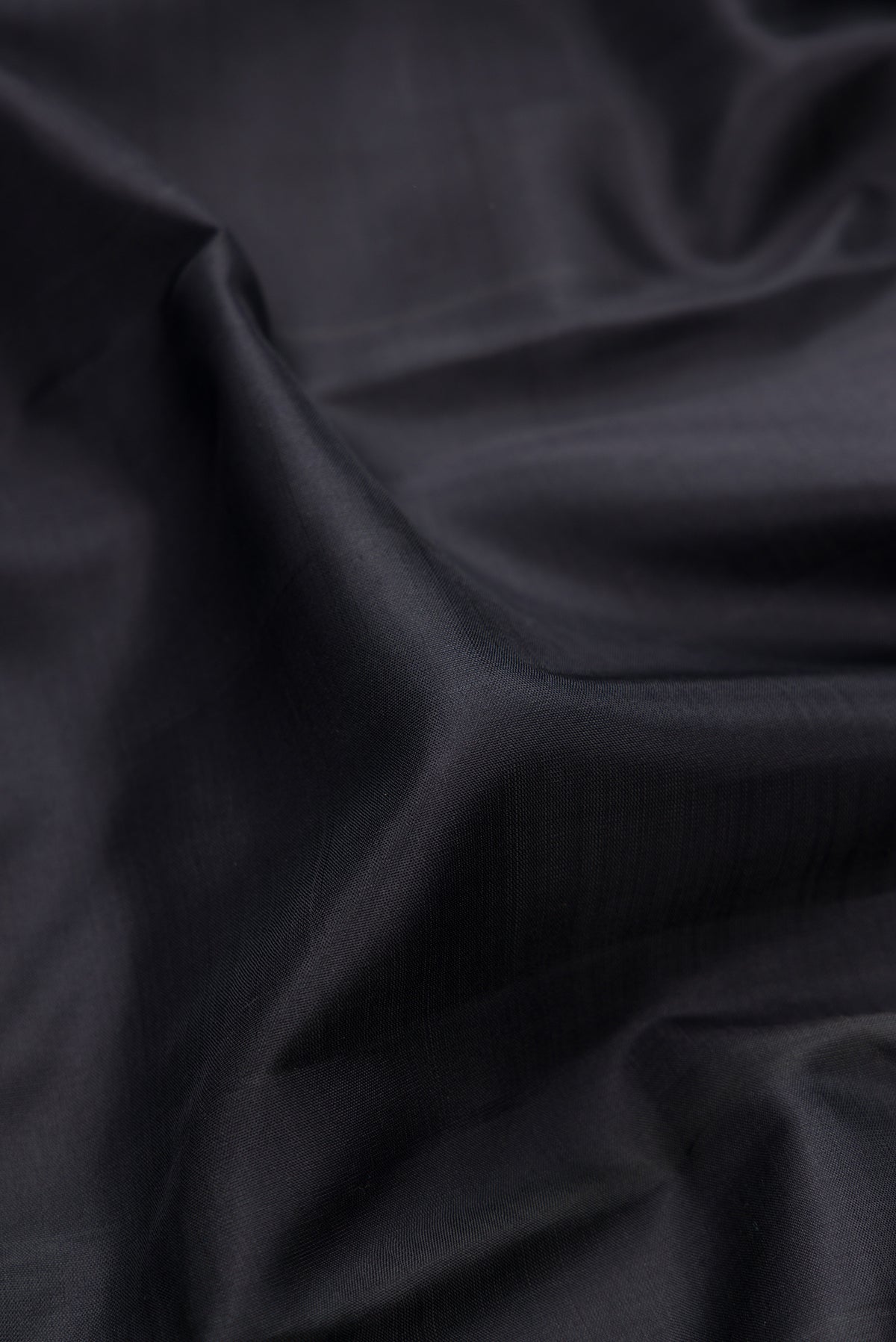 Close up of Black Kanjivaram Silk Saree with Plain Body and Thread Border.  displaying folds