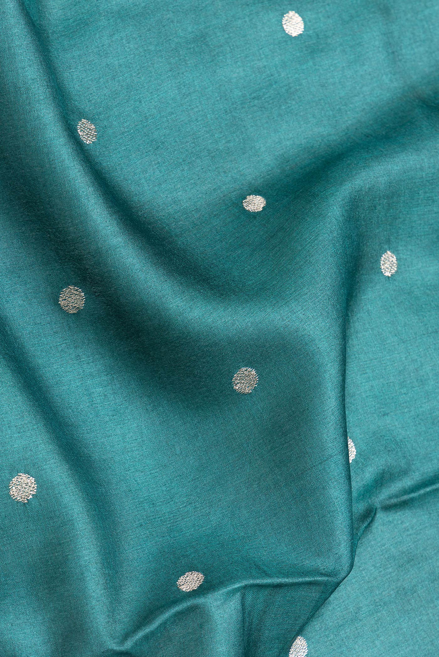 Close up of Green Dual Tone Tussar Silk Saree with Zari Butta on the body and Zari And Thread Border.  displaying folds