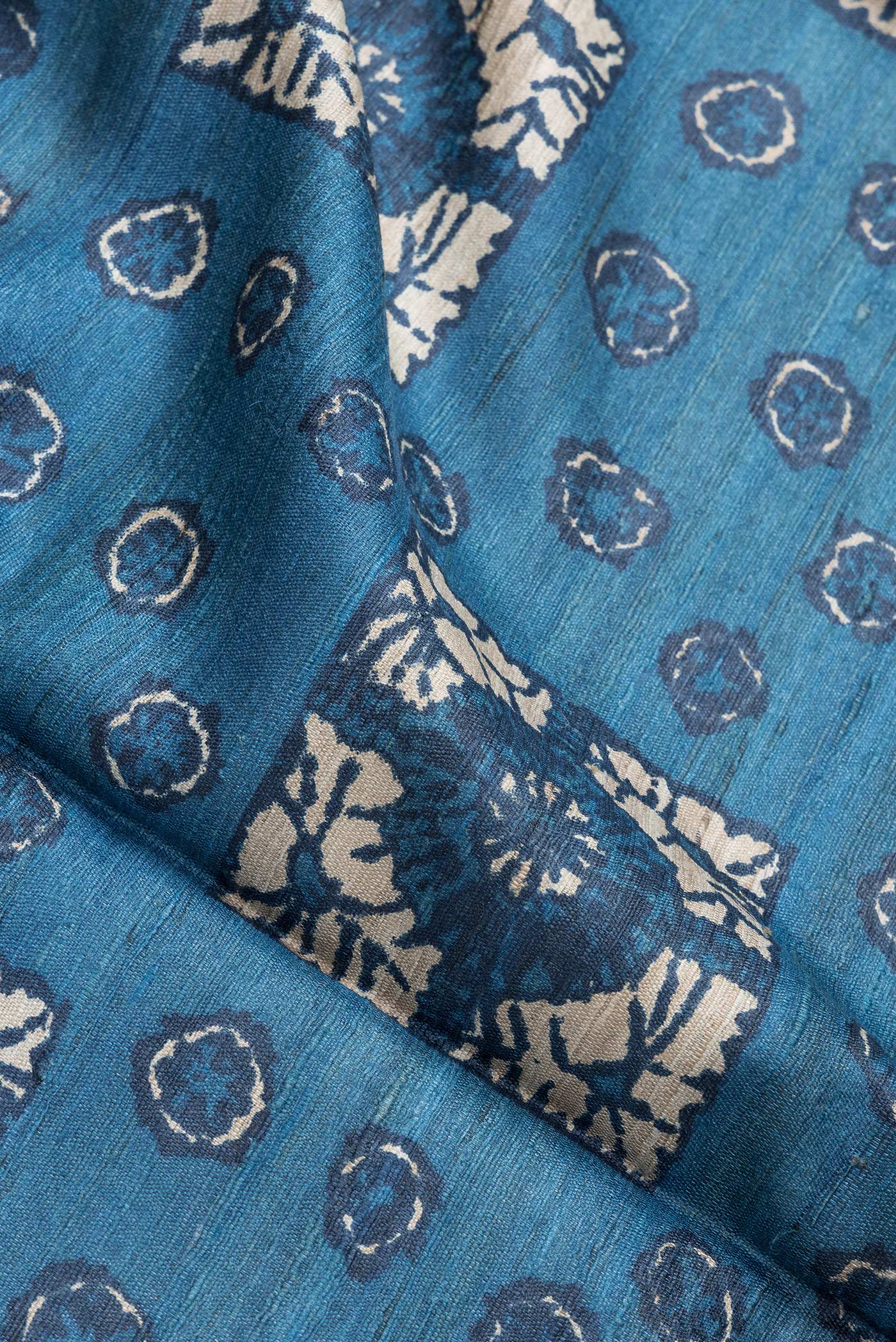 Close up of Blue Dual Tone Tussar Silk Saree with Printed design on the body and Without Border.  displaying folds
