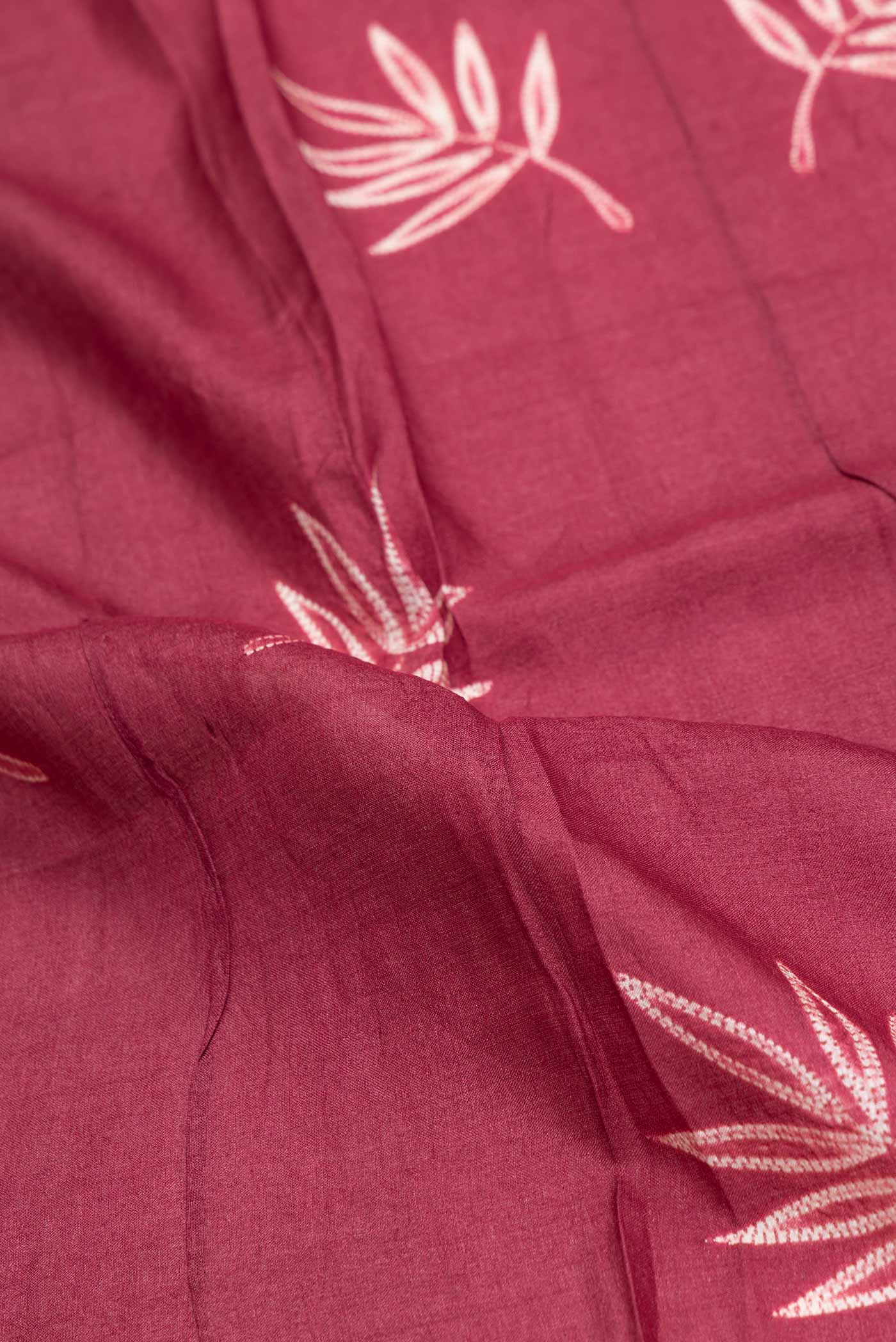 Close up of Maroon Dual Tone Tussar Saree with Printed design on the body and Zari Border.  displaying folds