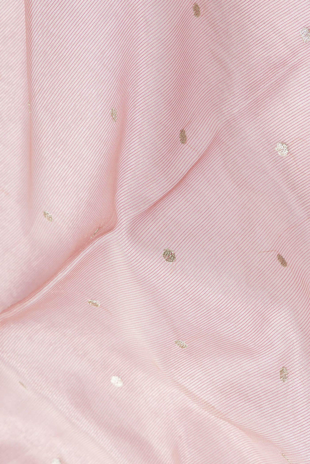 Close up of Rose Gold Dual Tone Organza Silk Saree with Zari Butta on the body and Embroidery Border.  displaying folds
