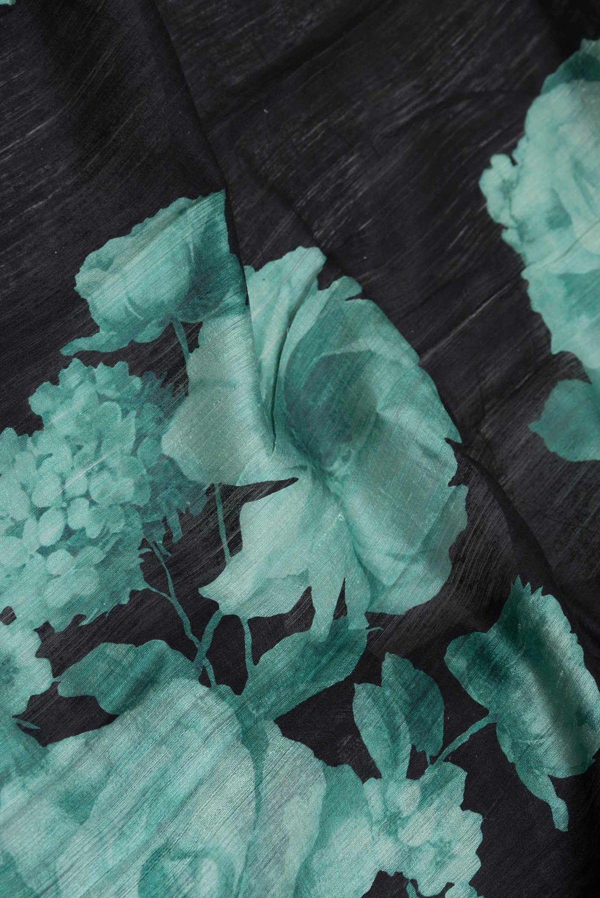 Close up of Black Dual Tone Tussar Silk Saree with Printed design on the body and Zari Border displaying folds