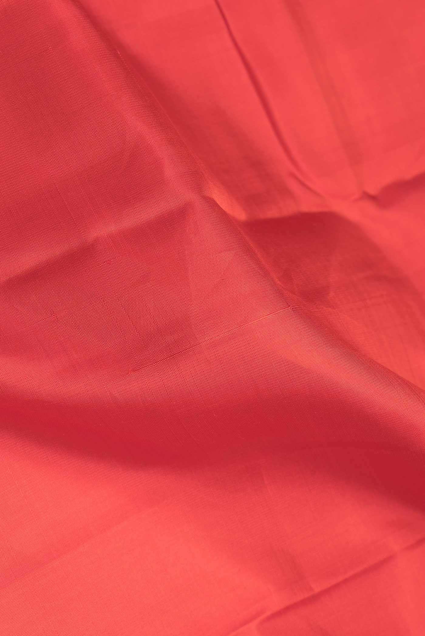 Close up of Red Dual Tone Kanchipuram Saree with Plain Body and Zari Border.  displaying folds