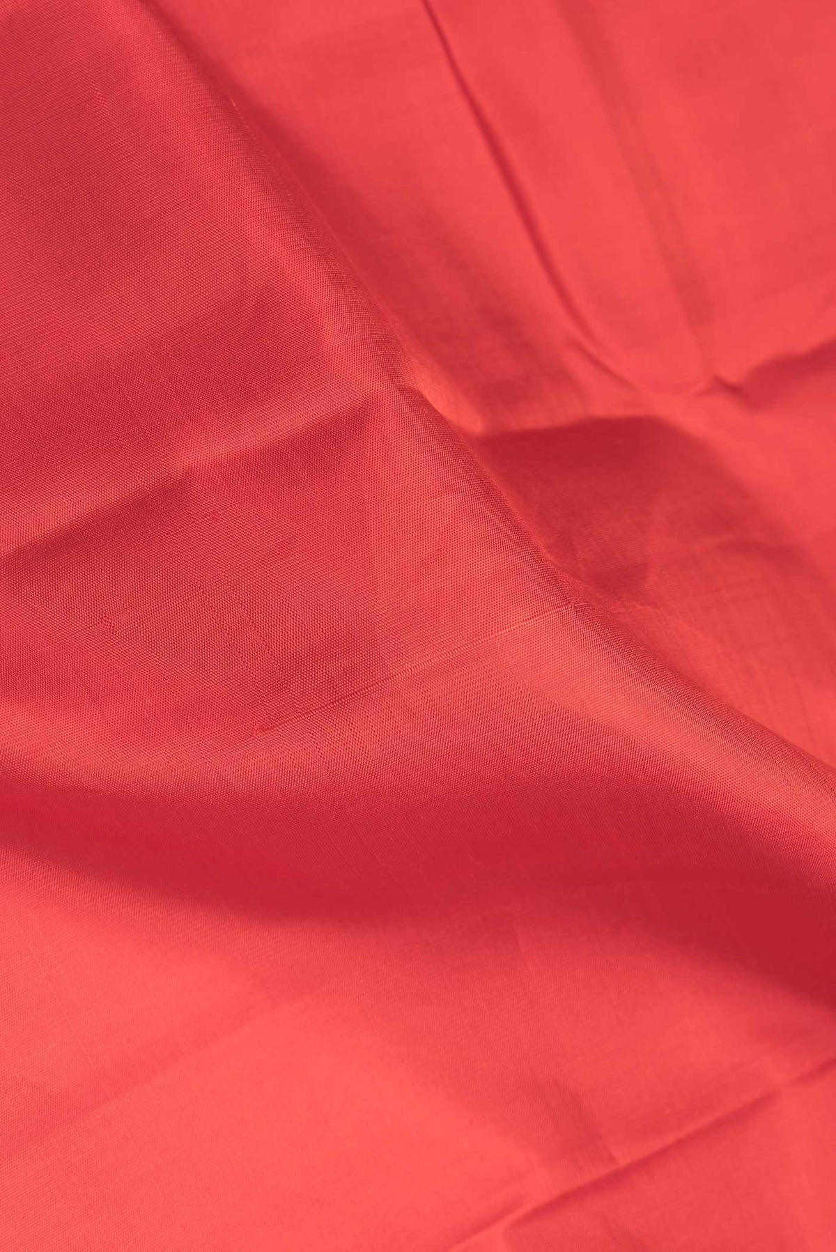 Close up of Red Dual Tone Kanchipuram Saree with Plain Body and Zari Border.  displaying folds