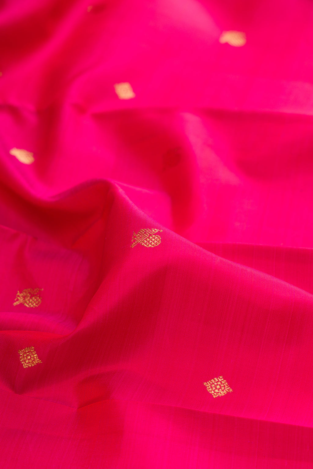 Close up of Pure Silk Dark Pink Kanjivaram Saree with Zari Butta on the body and Zari Border.  displaying folds