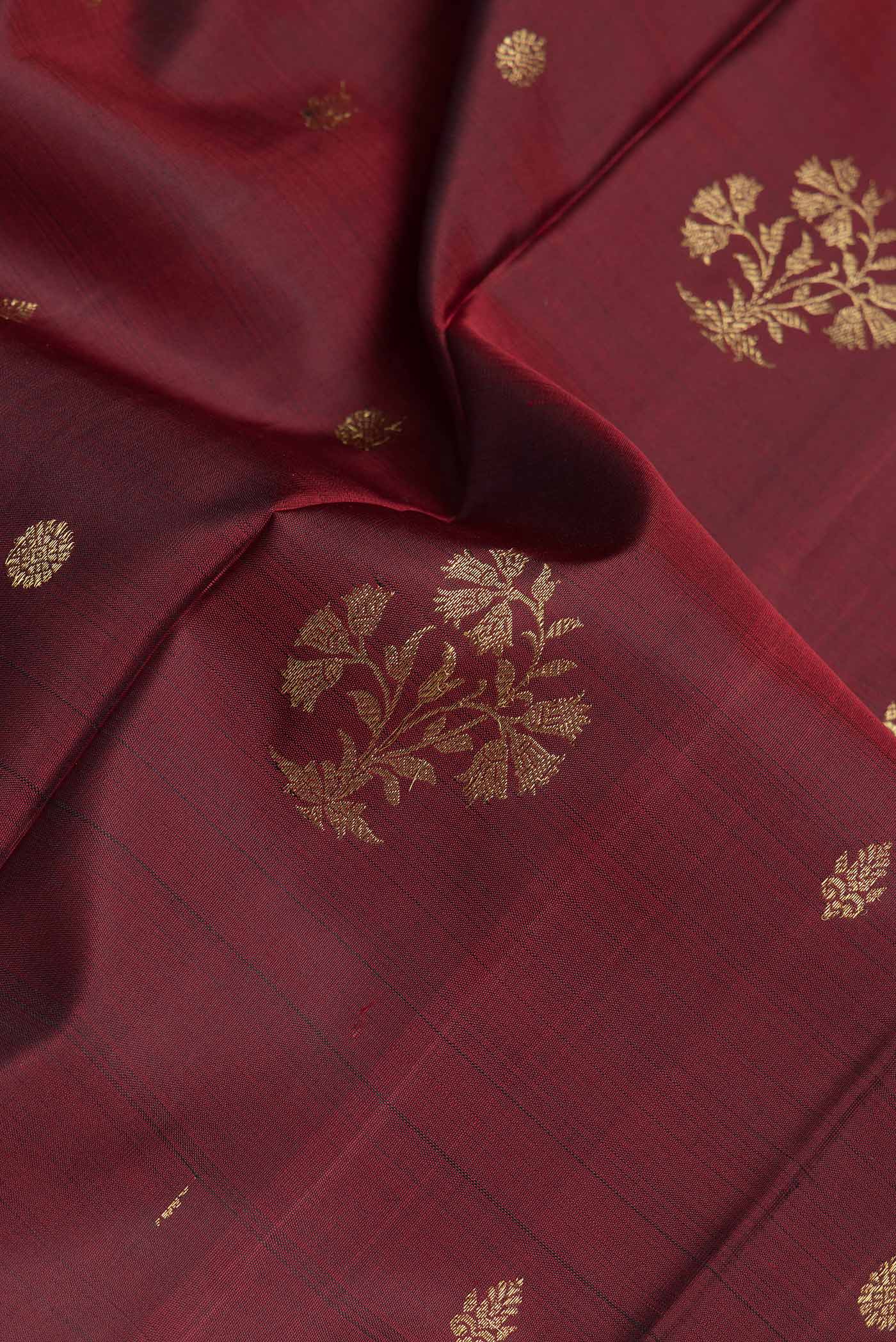 Close up of Maroon Dual Tone Kanchipuram Silk Saree with Zari Butta on the body and Zari Border.  displaying folds