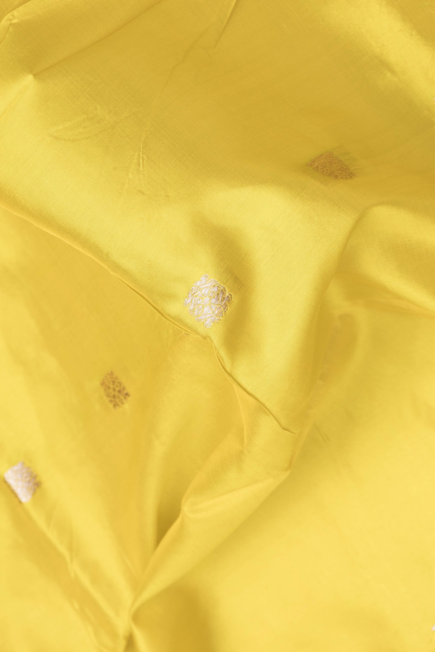 Close up of Yellow Dual Tone Banarasi Silk Saree with Zari Butta on the body and Zari Border.  displaying folds