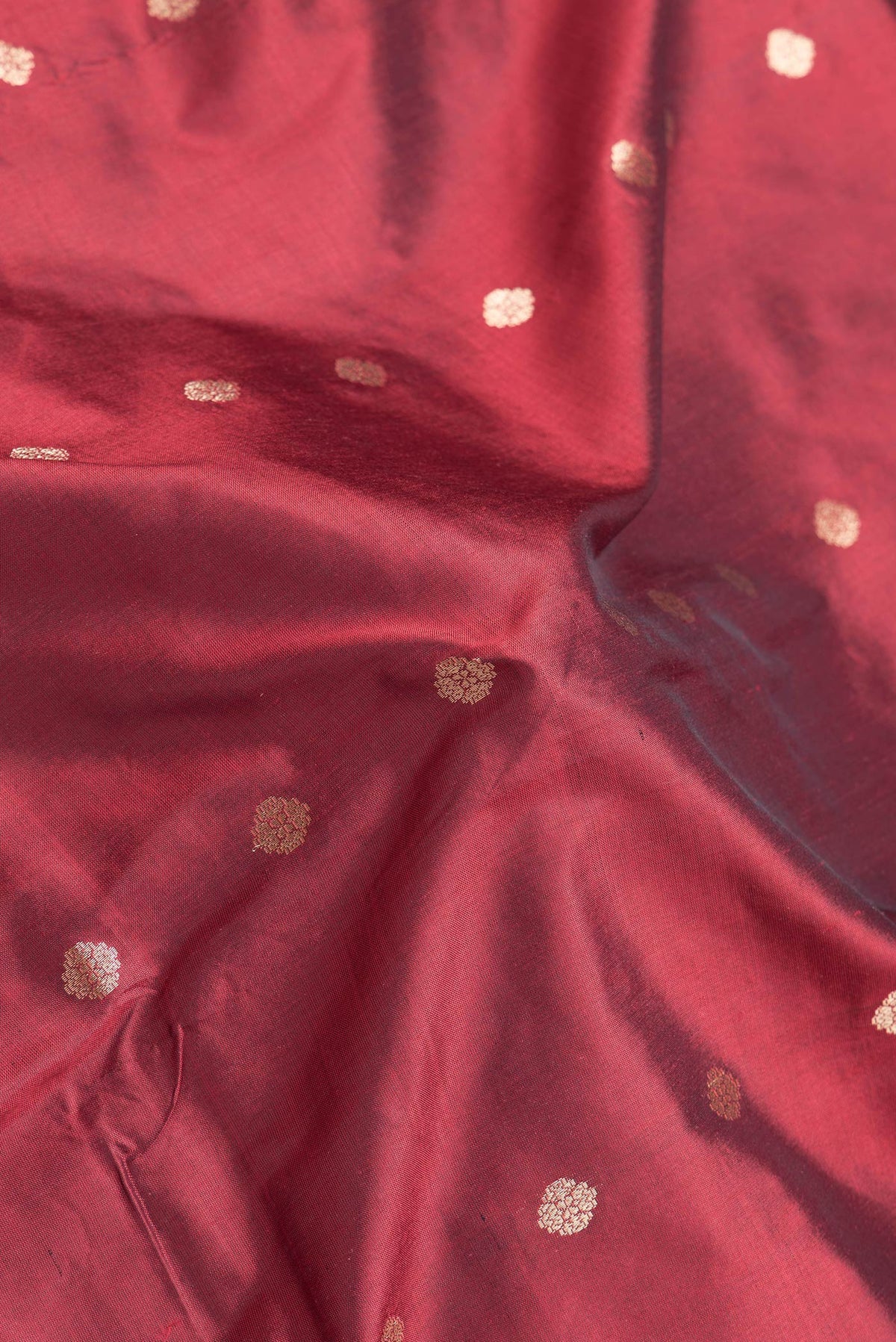 Close up of Maroon Dual Tone Banarasi Silk Saree with Zari Butta on the body and Zari Border.  displaying folds