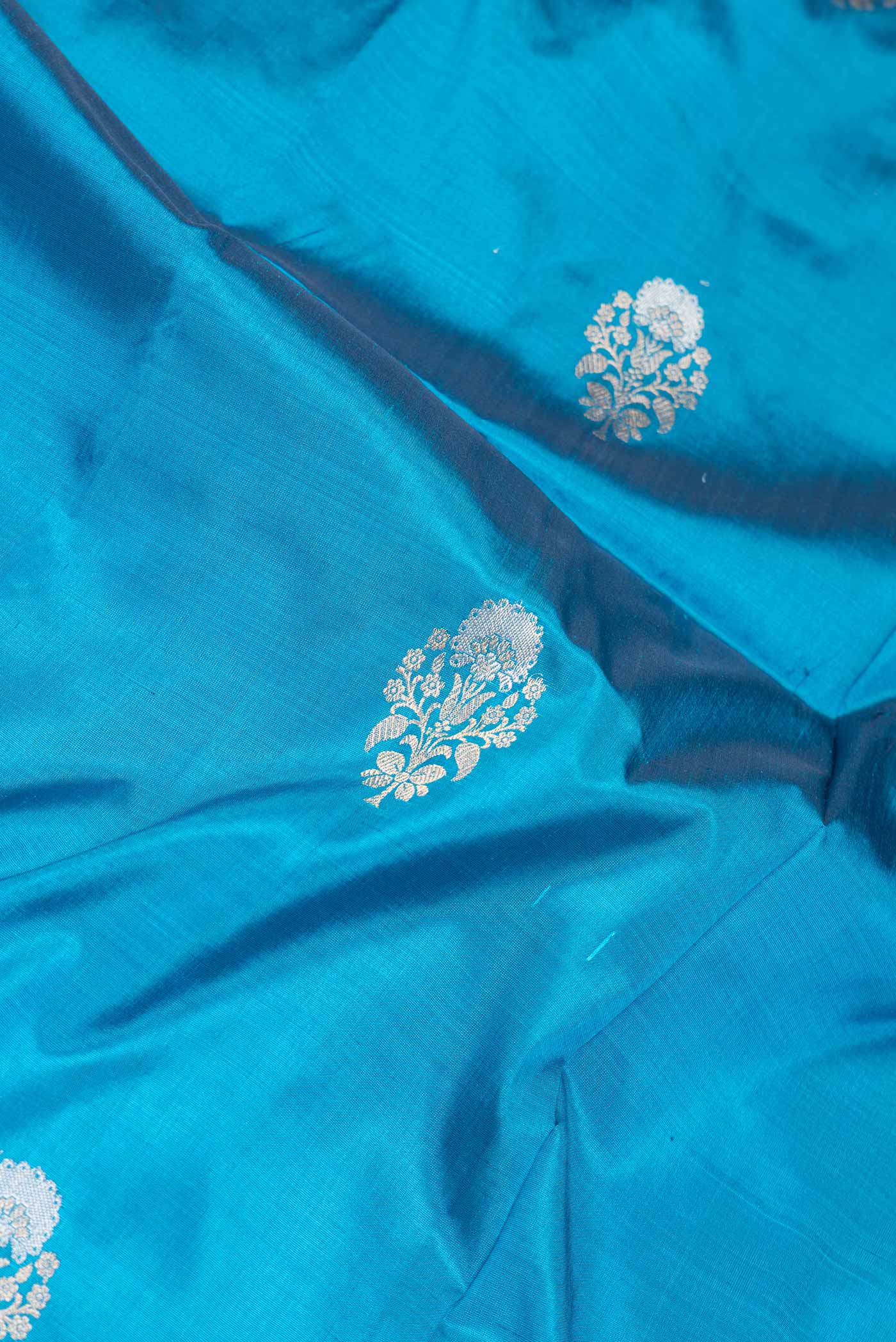 Close up of Peacock Blue Dual Tone Banarasi Silk Saree with Zari Butta on the body and Zari Border.  displaying folds