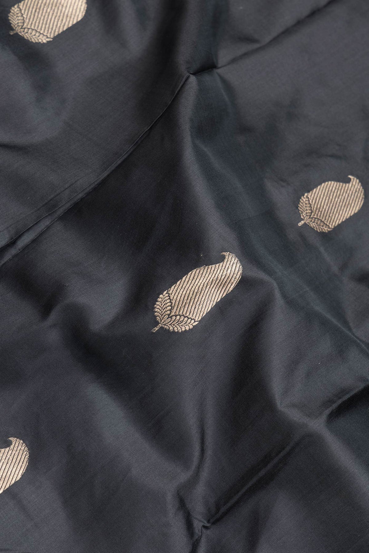 Close up of Black Dual Tone Banarasi Silk Saree with Zari Butta on the body and Zari Border.  displaying folds