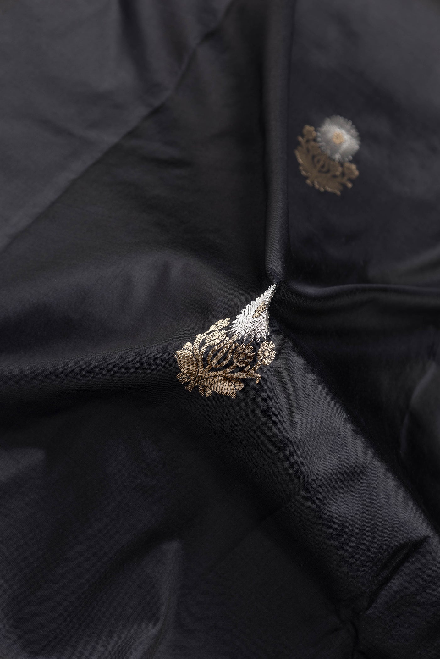 Close up of Black Dual Tone Banarasi Silk Saree with Zari Butta on the body and Zari Border.  displaying folds