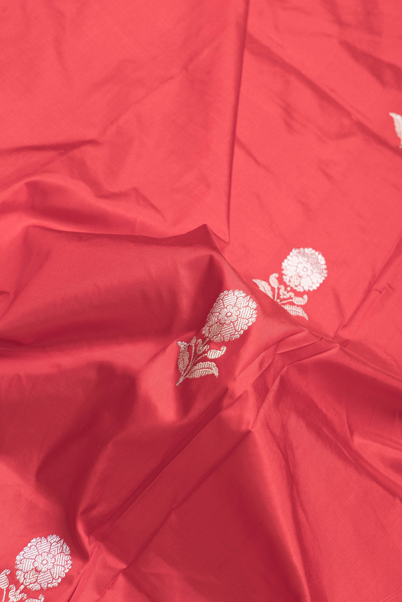 Close up of Red Dual Tone Banarasi Silk Saree with Zari Butta on the body and Thread Border.  displaying folds